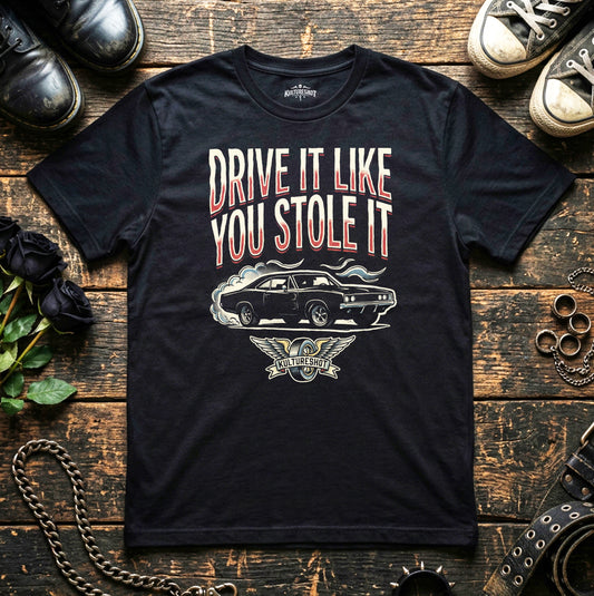 Black t-shirt with 'Drive It Like You Stole It' graphic on a wooden surface with shoes and a chain.