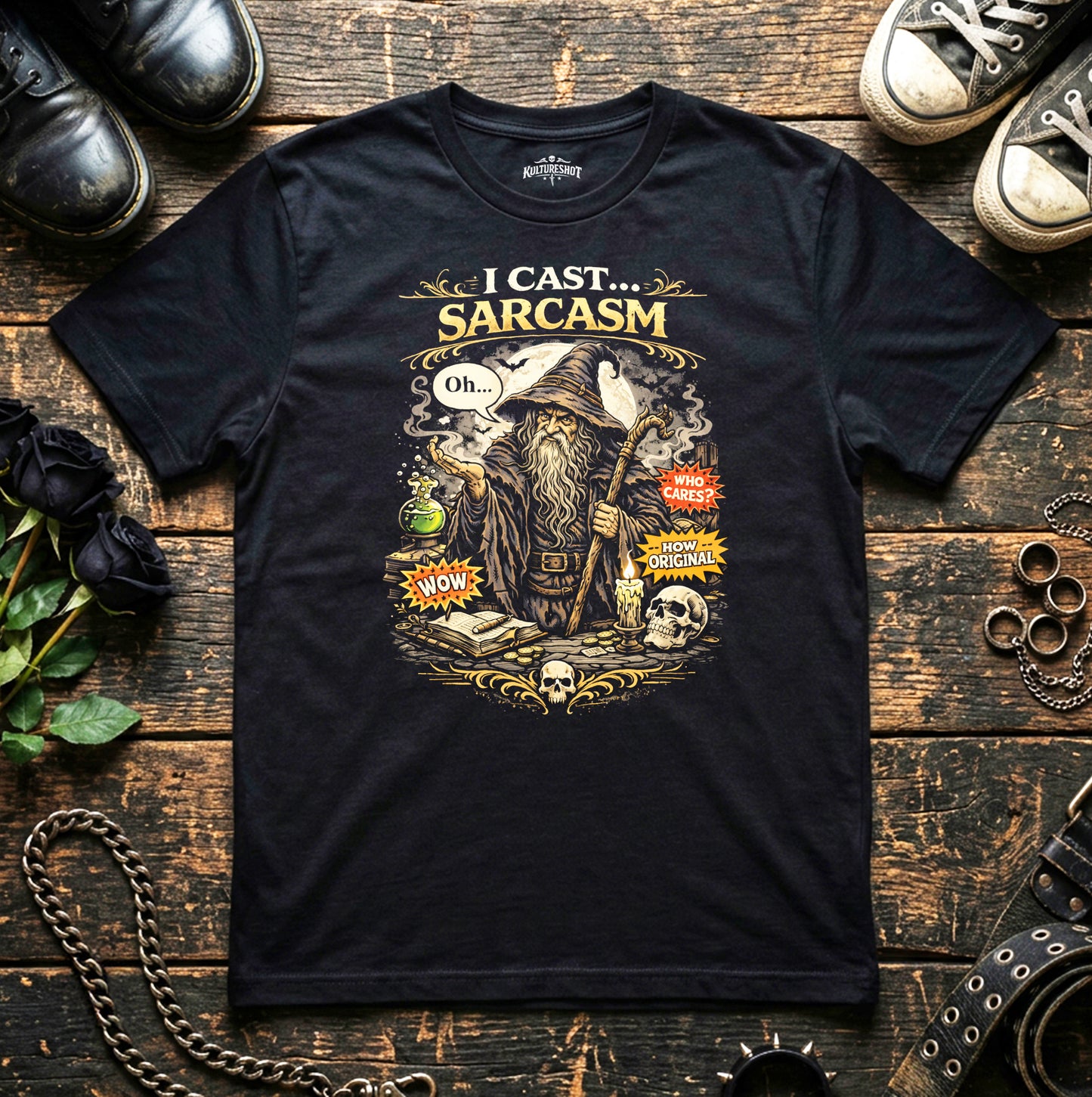Black t-shirt with a graphic design of a wizard and text 'I Cast Sarcasm' on a wooden surface with shoes and decorative items.
