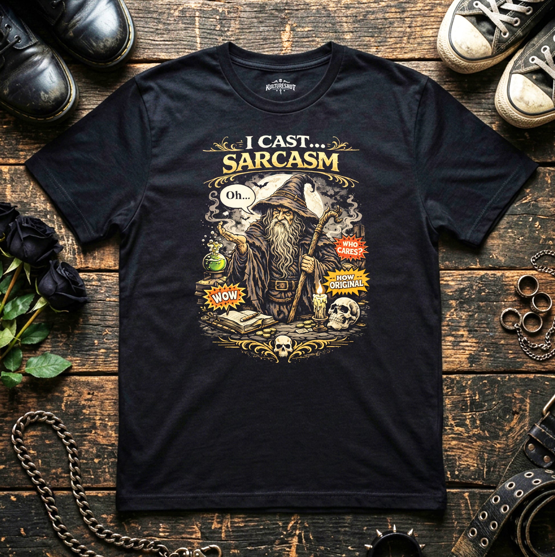 Black t-shirt with a graphic design of a wizard and text 'I Cast Sarcasm' on a wooden surface with shoes and decorative items.