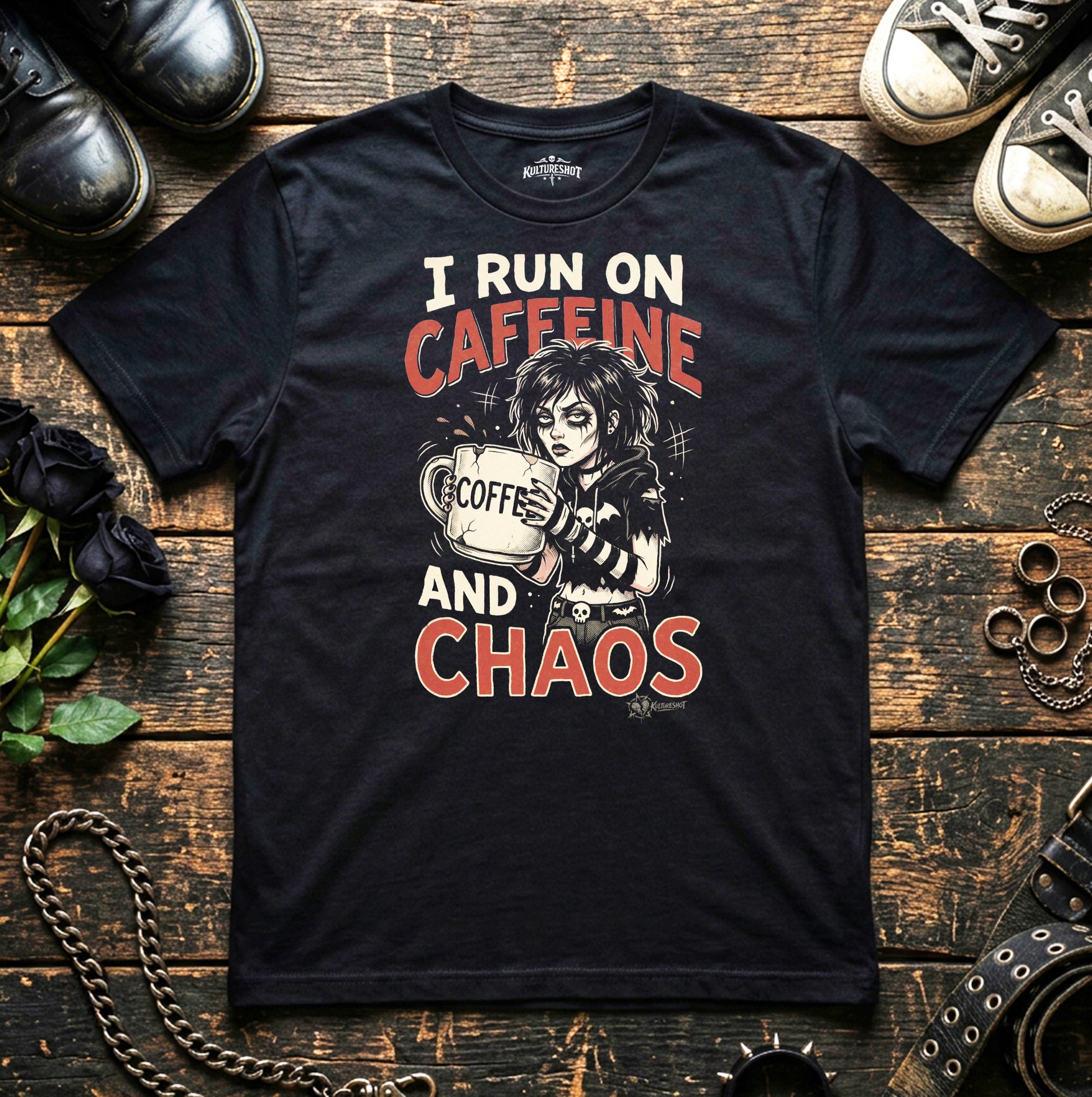 Black t-shirt with graphic design and text on a wooden surface with shoes and accessories.