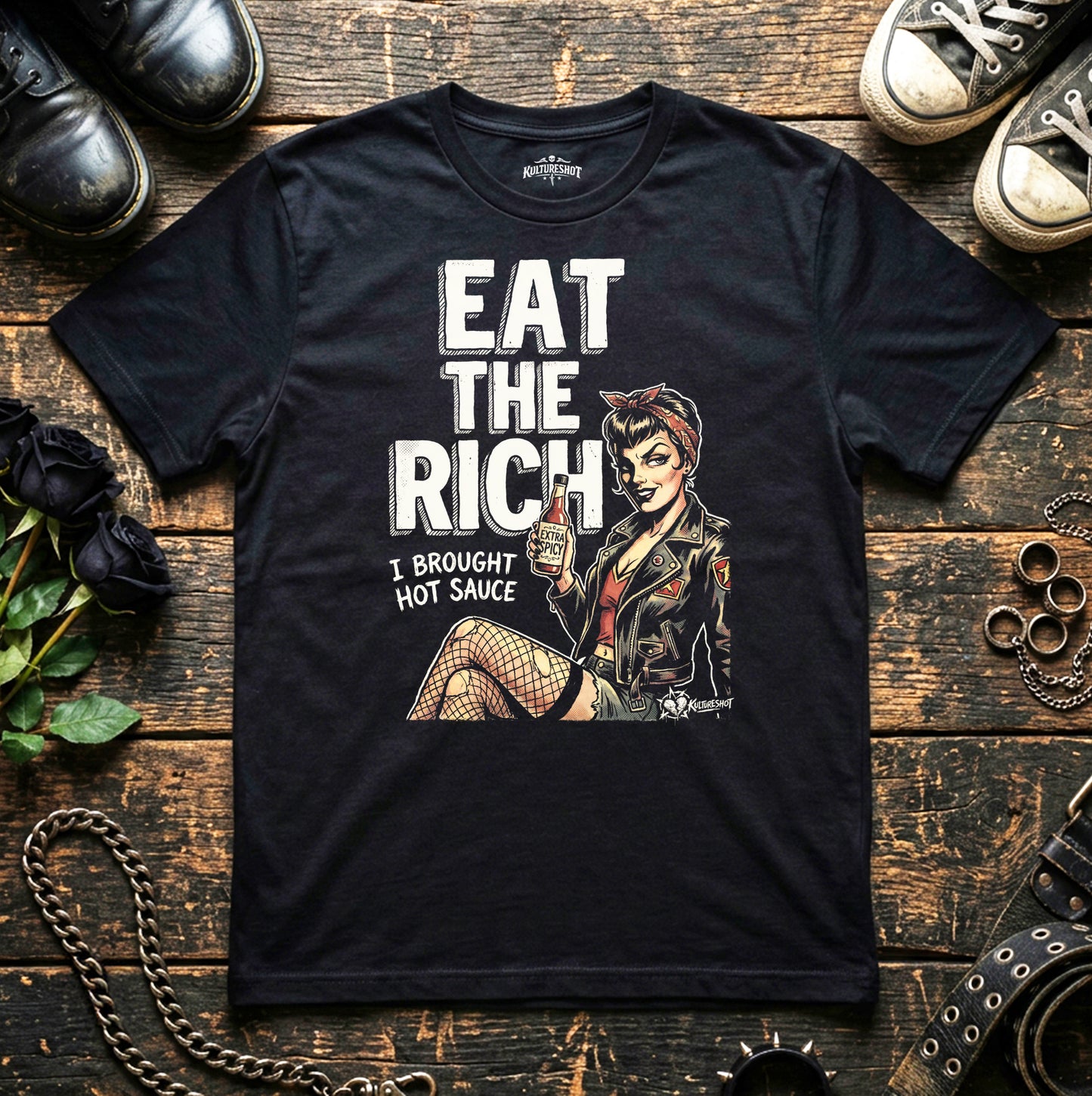 Black t-shirt with graphic design and text on a wooden surface with shoes and a camera.