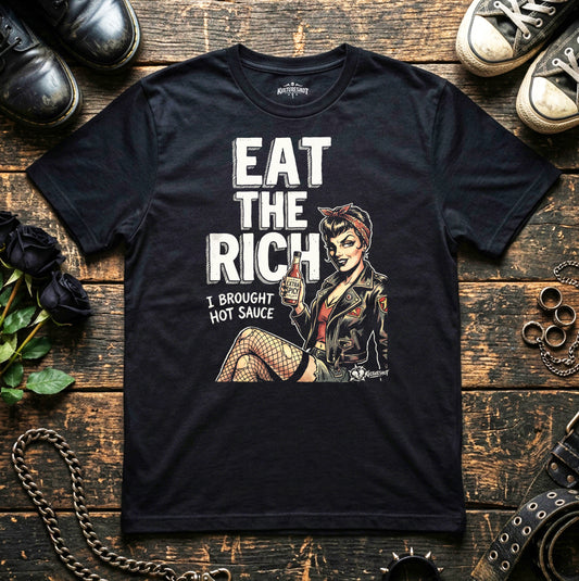 Black t-shirt with graphic design and text on a wooden surface with shoes and a camera.