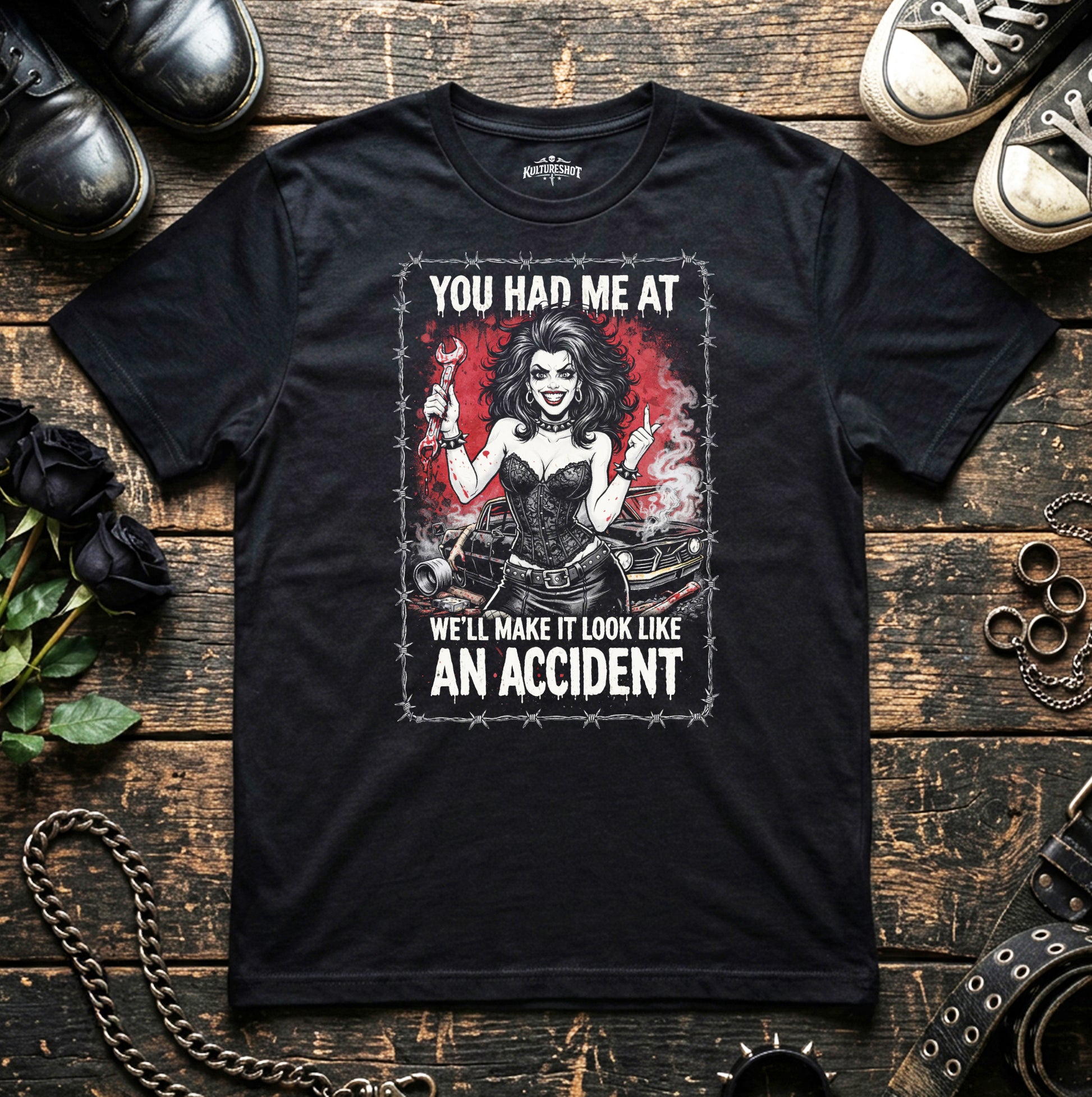 Black t-shirt with graphic design and text on a wooden surface with shoes and roses.