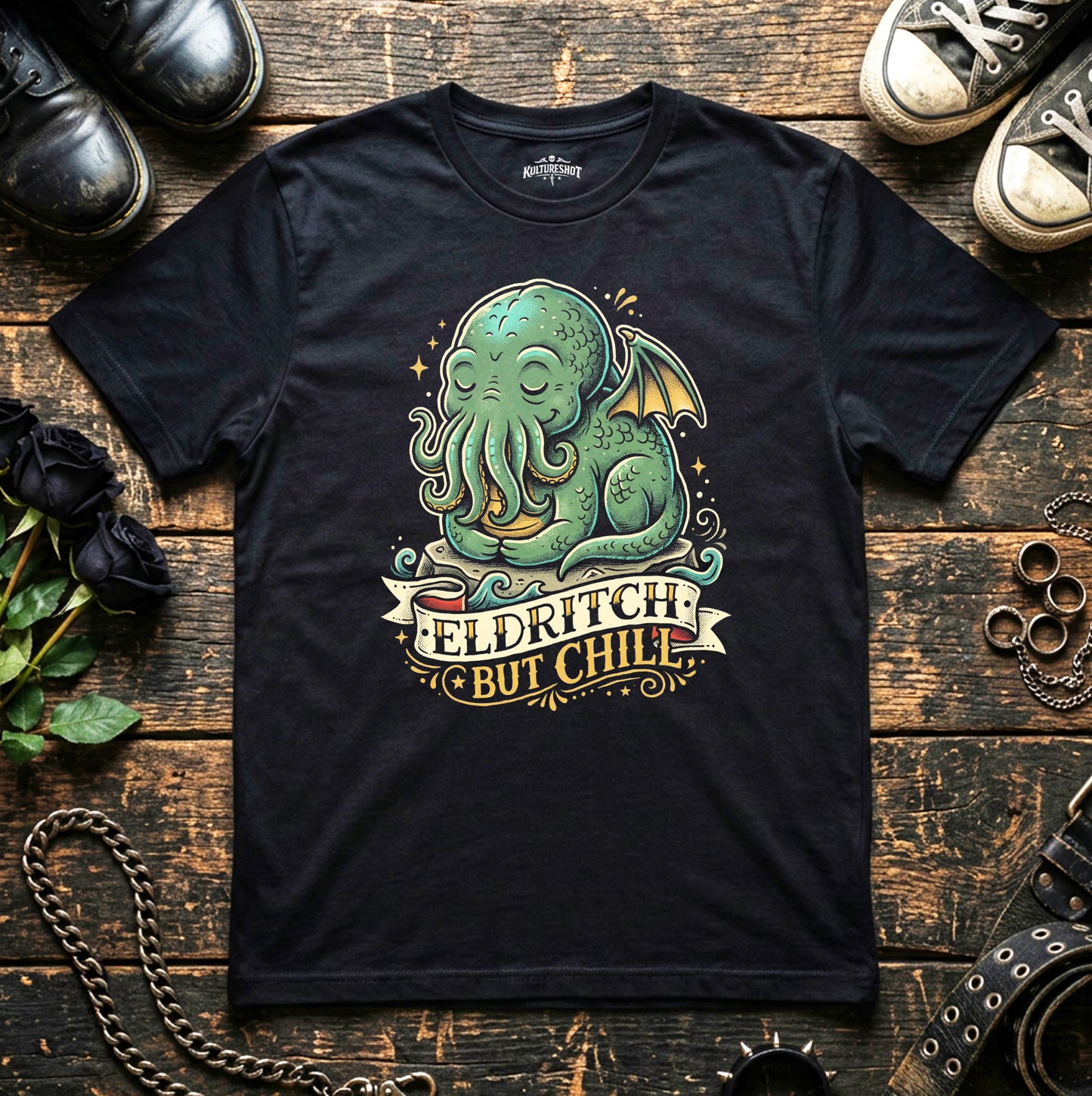Black t-shirt with a green Cthulhu design and 'Eldritch But Chill' text on a wooden surface.