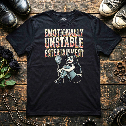 Black t-shirt with graphic design and text on a wooden surface with shoes and flowers.