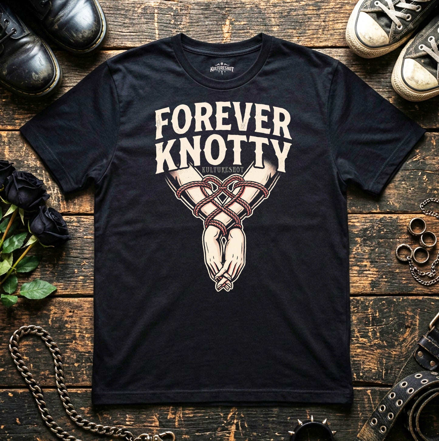 Black t-shirt with 'Forever Knotty' design on a wooden surface with shoes and jewelry.
