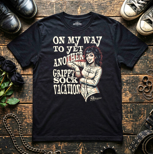 Black t-shirt with graphic design and text on a wooden surface with shoes and roses.