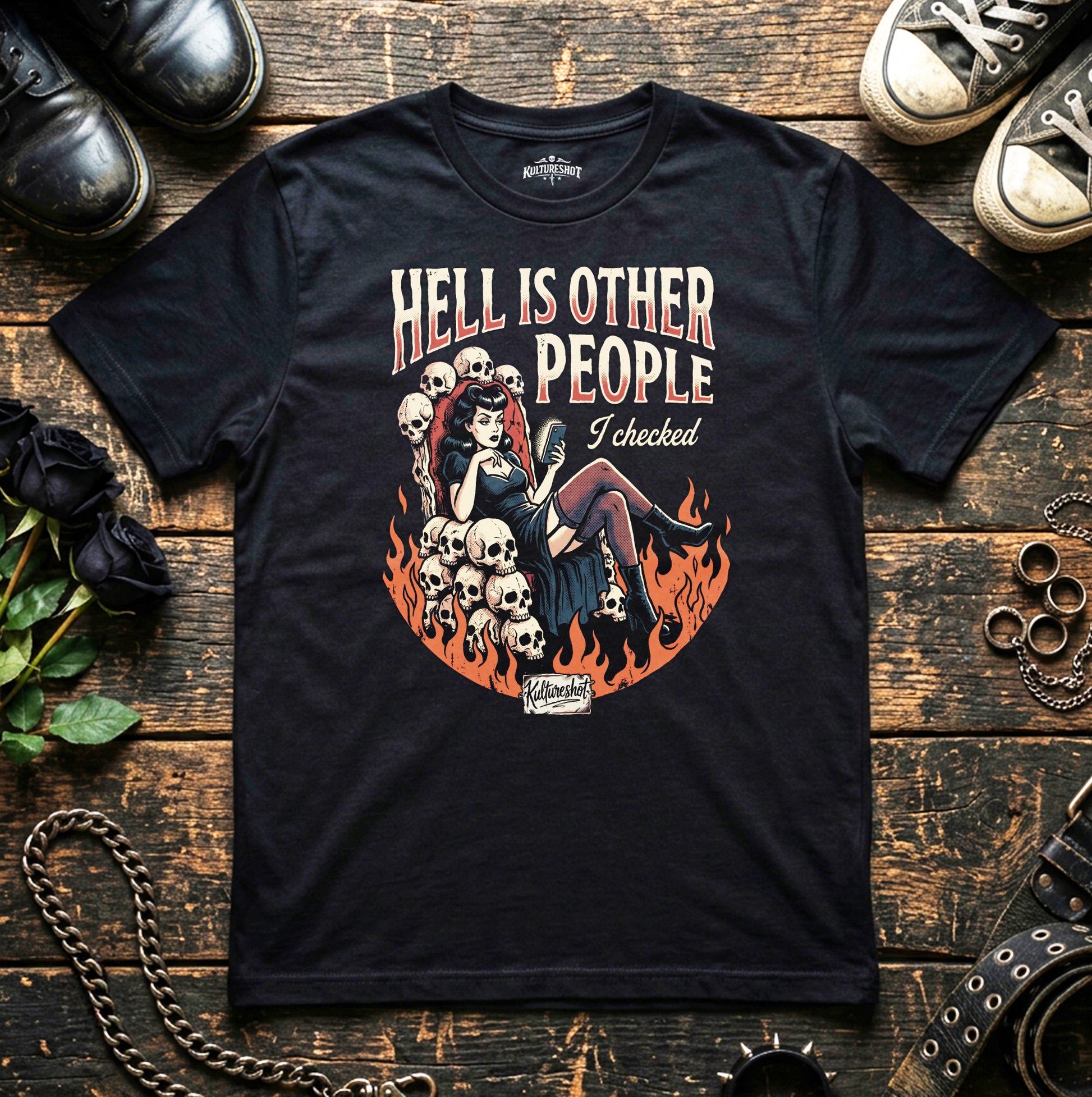 Black t-shirt with graphic design and text on a wooden surface with shoes and roses.
