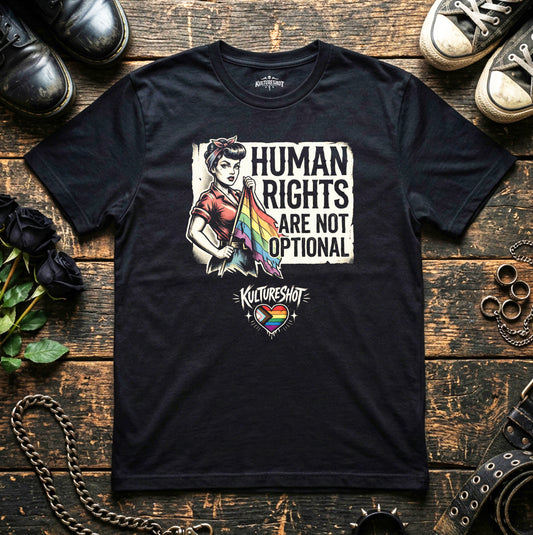 Black t-shirt with a graphic design on a wooden surface with shoes and flowers.