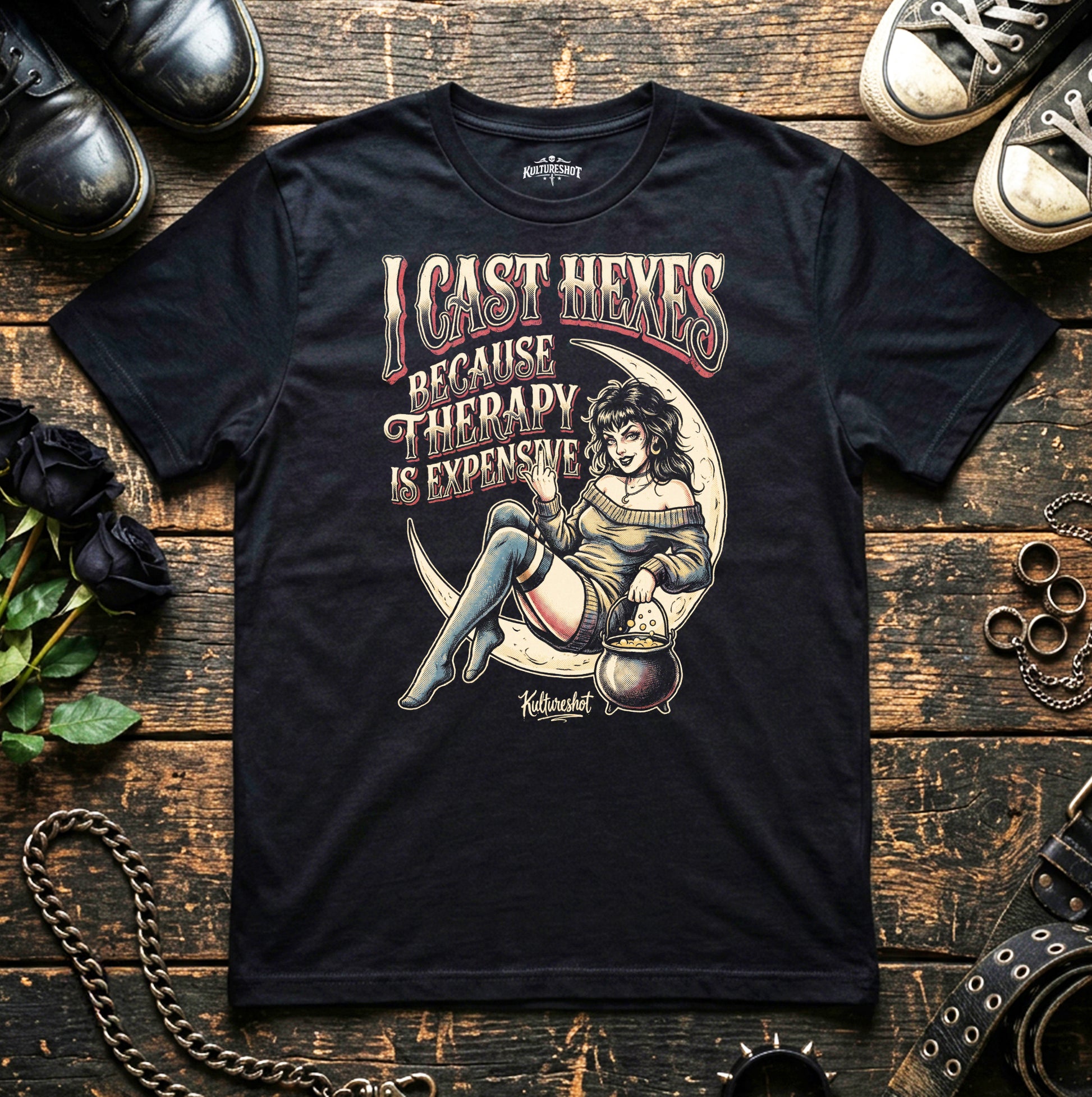 Black t-shirt with graphic design and text on a wooden surface with shoes and decorative items.