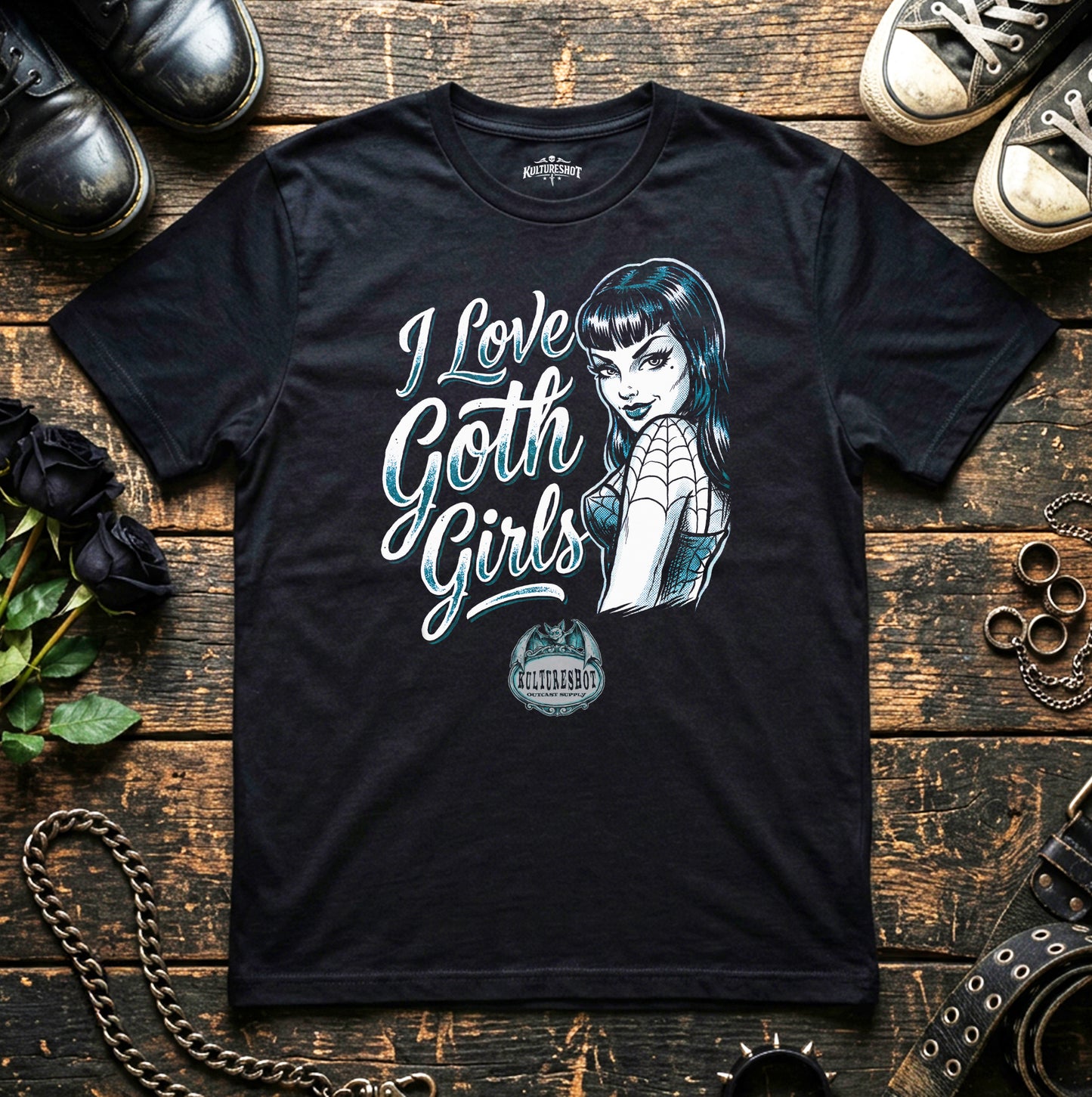 Black t-shirt with 'I Love Goth Girls' design on a wooden surface with shoes and roses.
