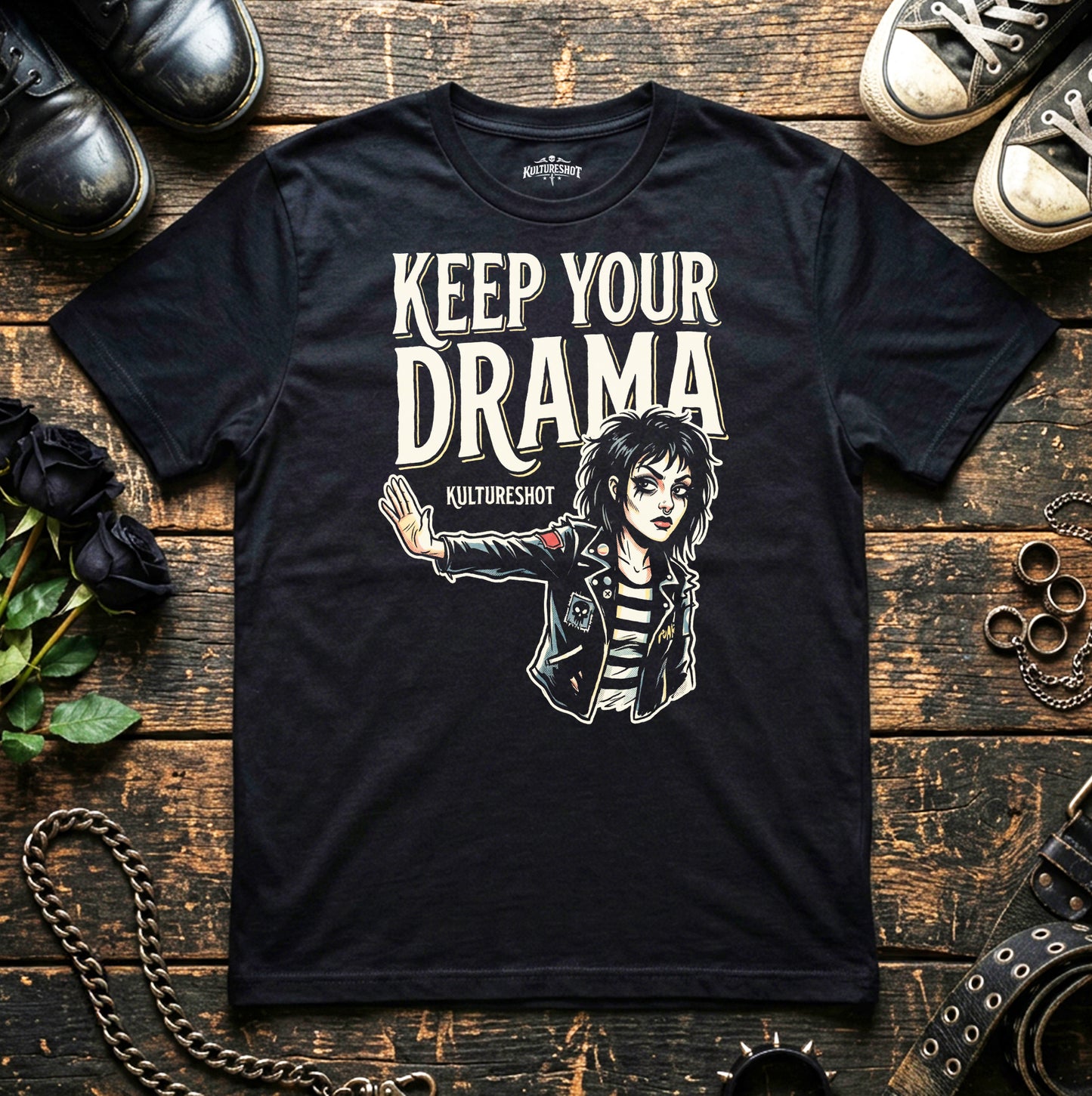 Black t-shirt with graphic design and text on a wooden surface with shoes and accessories.