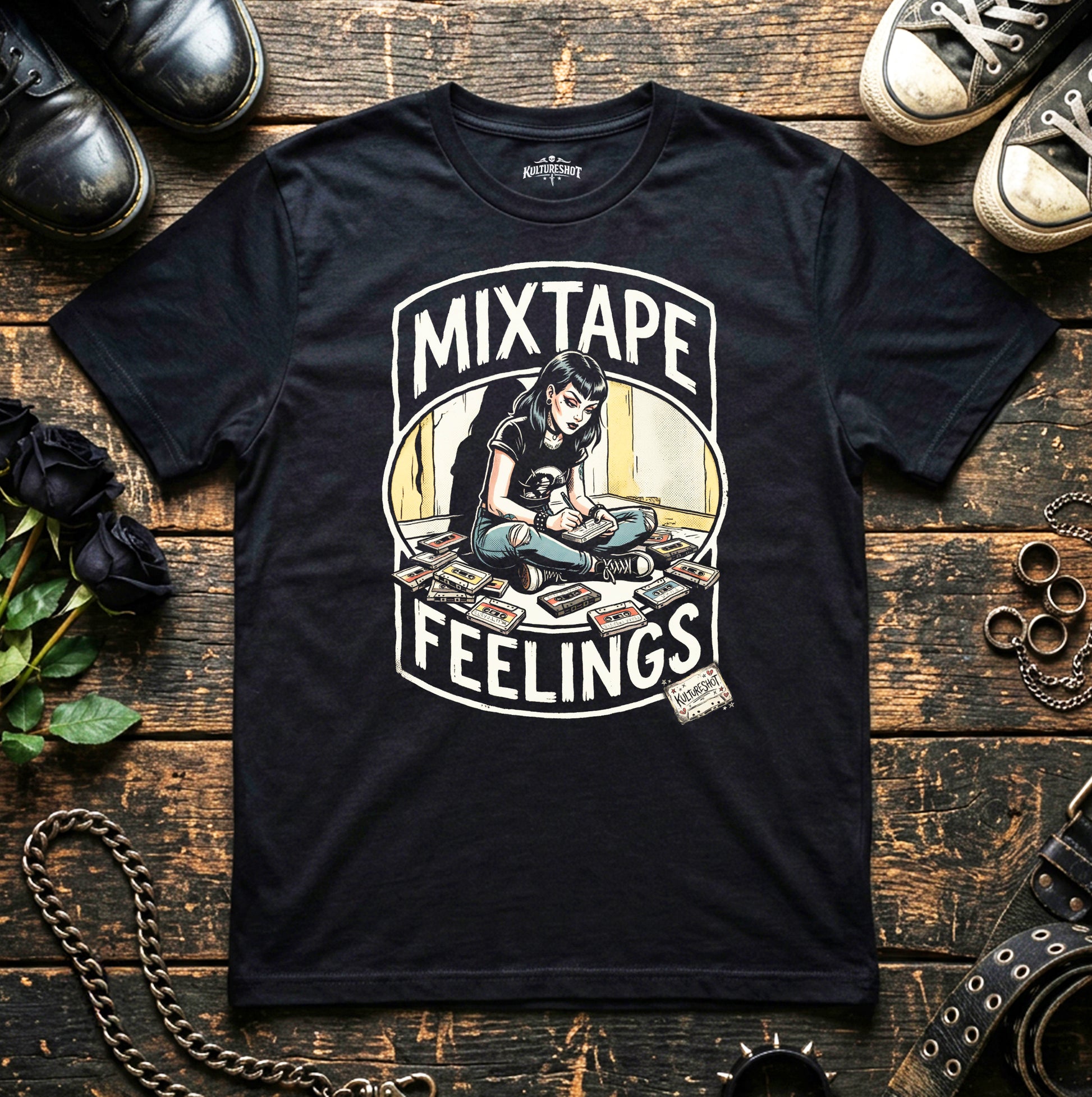 Black t-shirt with 'Mixtape Feelings' graphic design on a wooden surface with shoes and a chain.