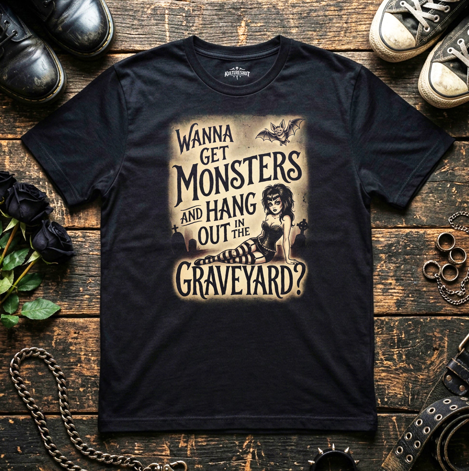 Black t-shirt with graphic design and text on a wooden surface with shoes and decorative items.