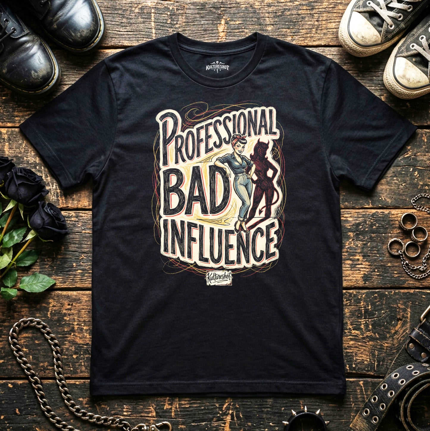 Black t-shirt with 'Professional Bad Influence' design on a wooden surface with shoes and roses.