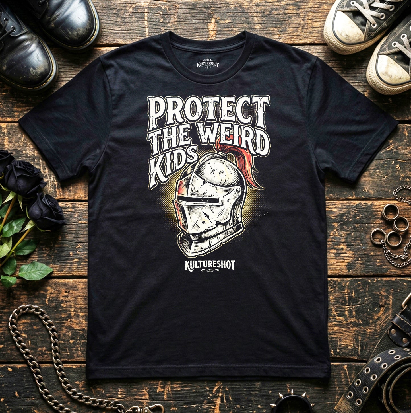 Black t-shirt with 'Protect the Weird Kids' graphic on a wooden surface with shoes and chains.