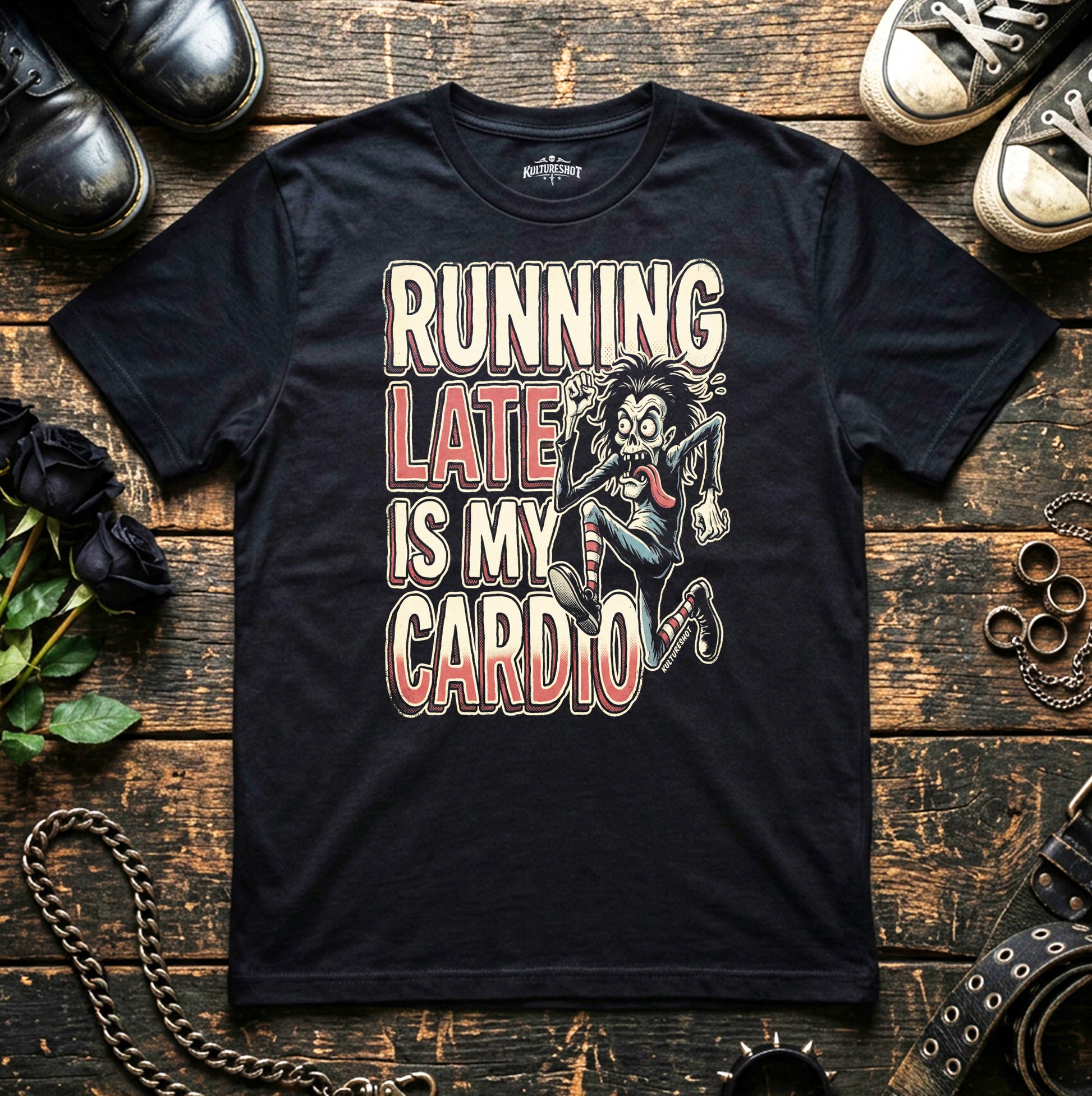Black t-shirt with graphic design and text on a wooden surface with shoes and accessories.