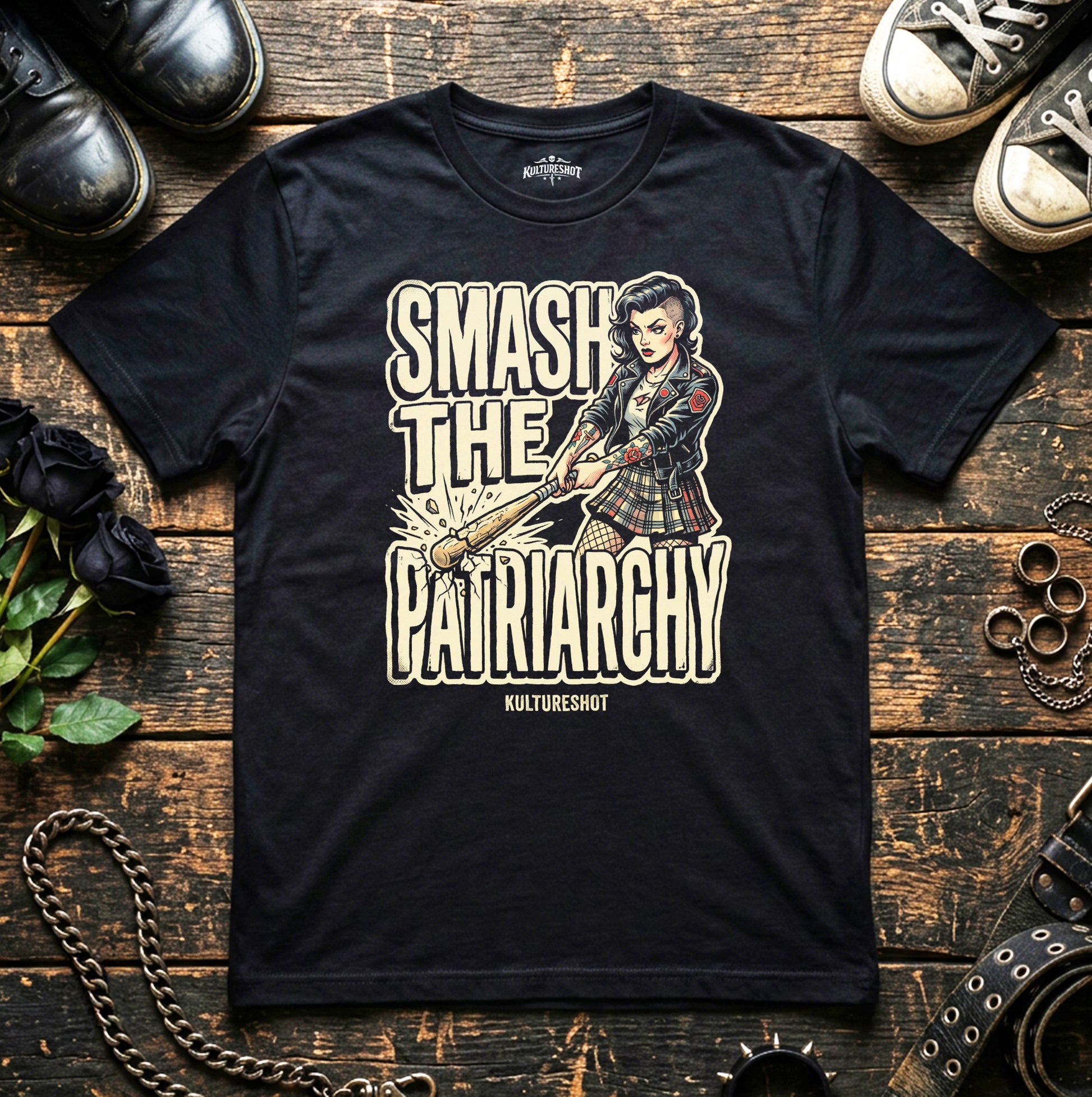 Black t-shirt with graphic design and text on a wooden surface with shoes and flowers.