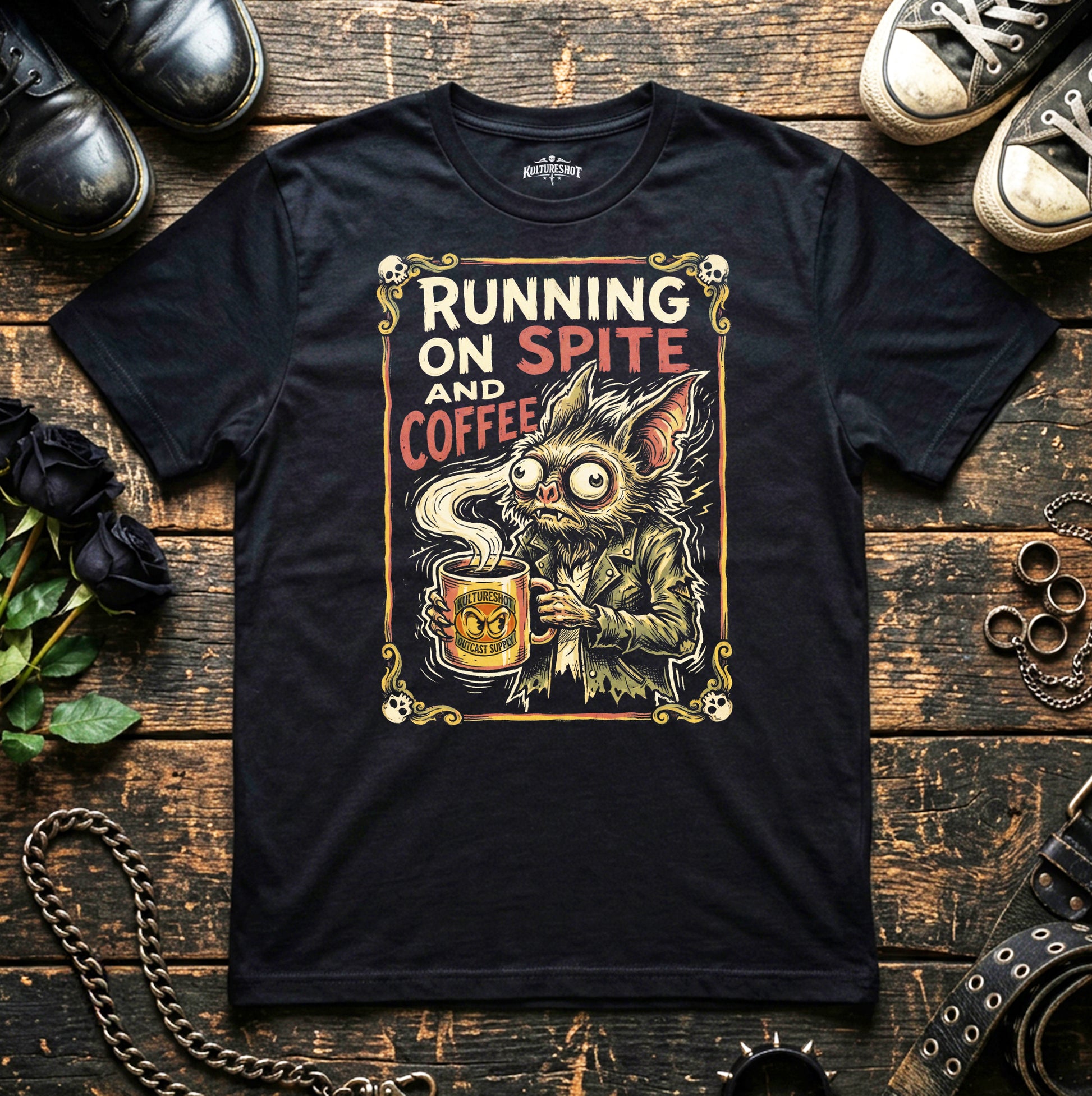 Black t-shirt with a graphic design of a creature holding a coffee cup and text 'Running on Spite and Coffee' on a wooden surface.