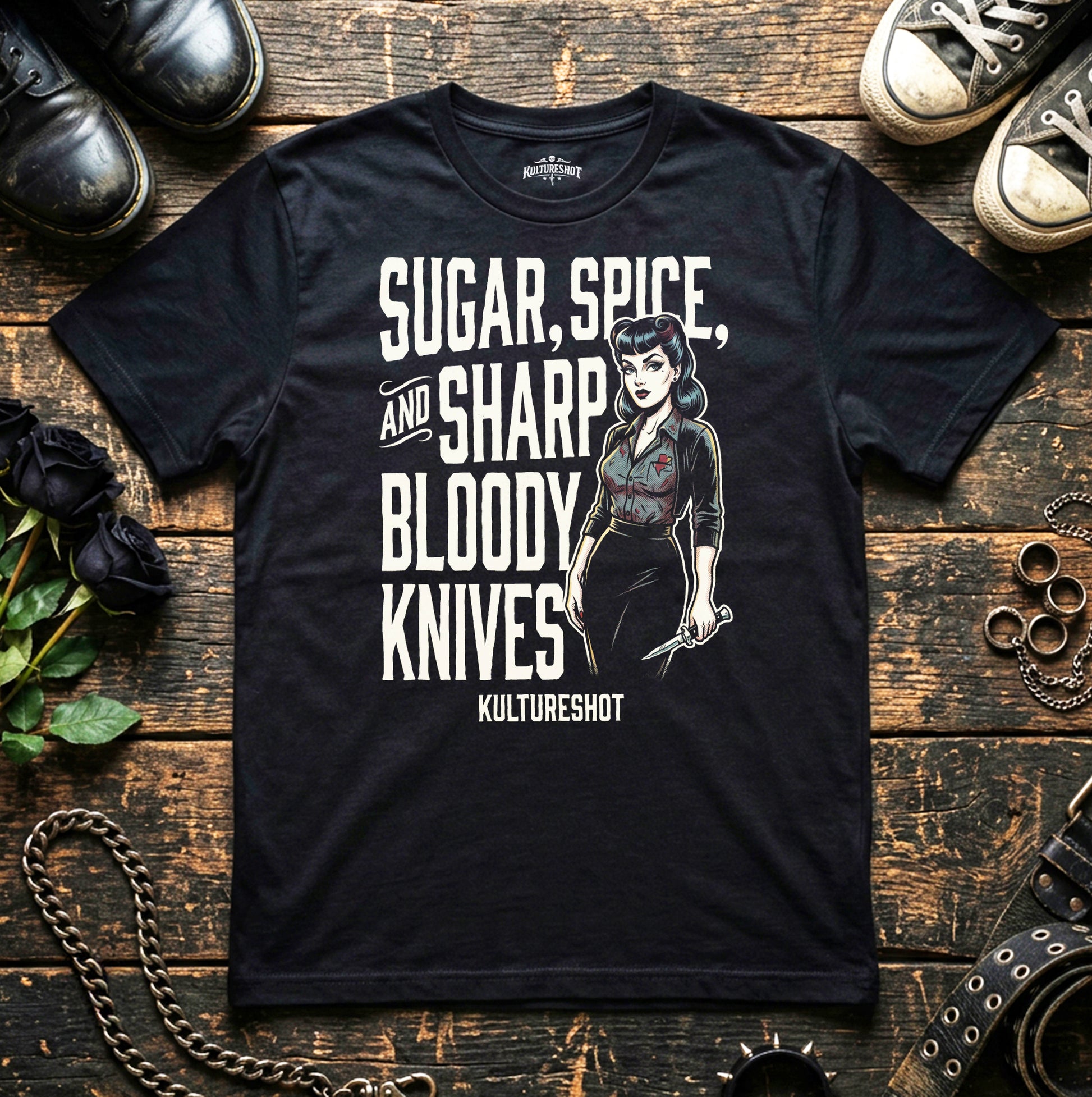 Black t-shirt with graphic design and text on a wooden surface with shoes and roses.