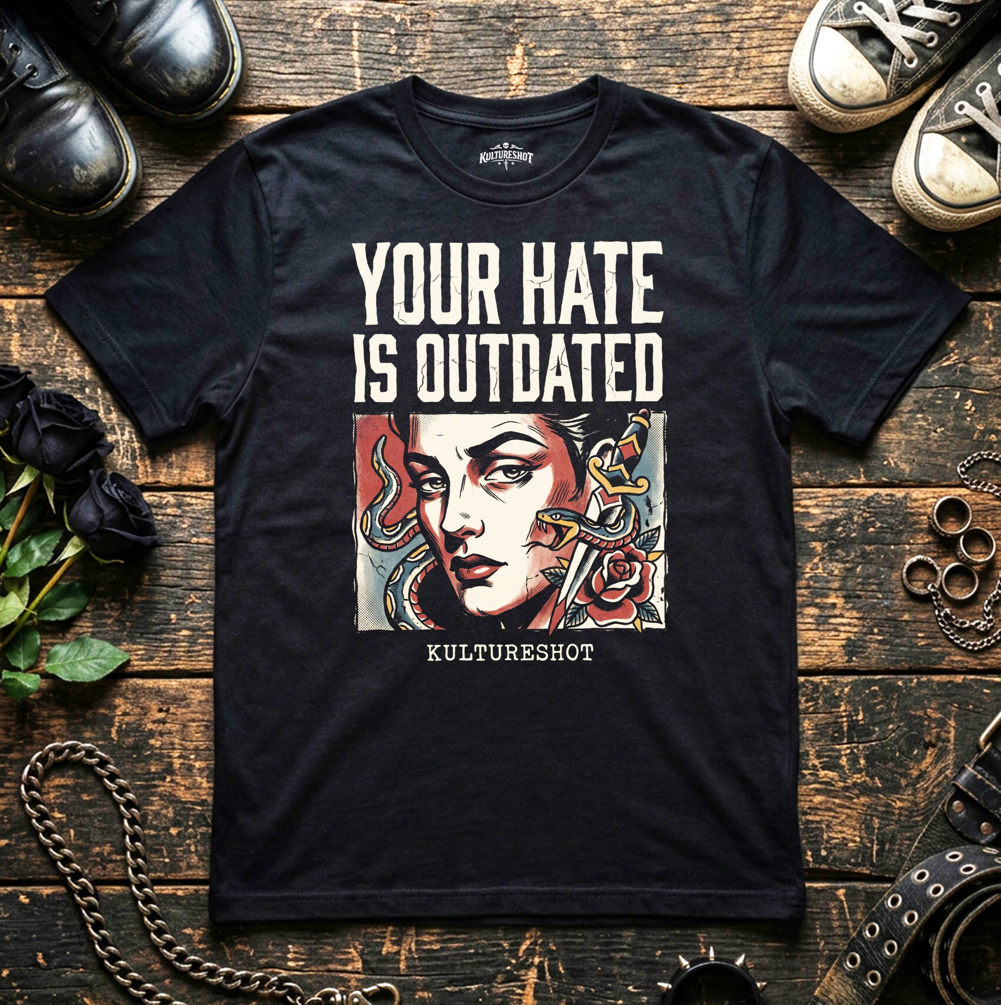 Black t-shirt with graphic design and text on a wooden surface with shoes and roses.