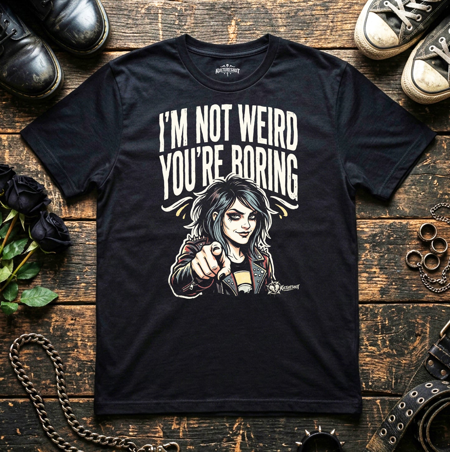 Black t-shirt with graphic design and text on a wooden surface with shoes and chains.