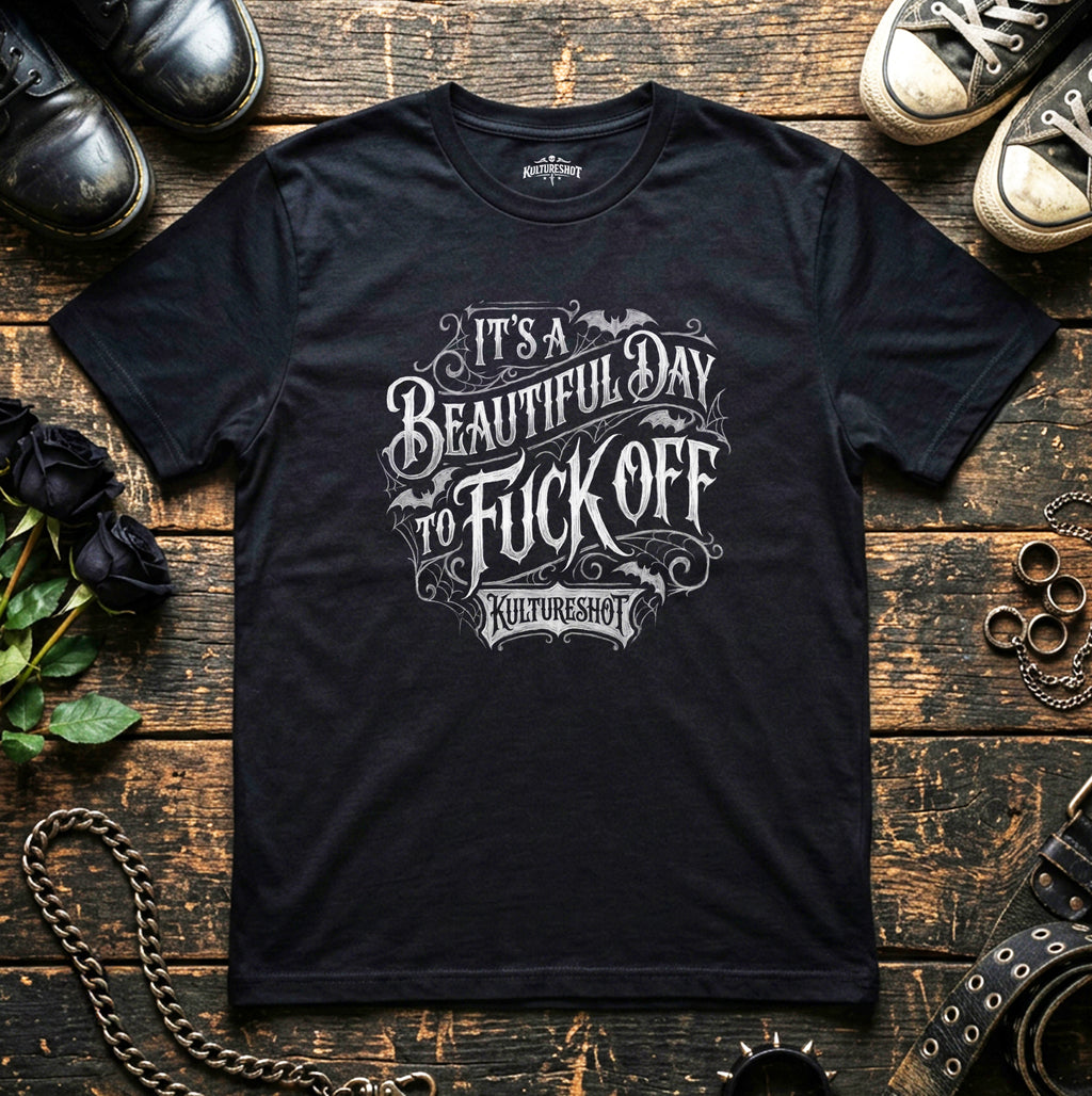 Black t-shirt with graphic text on a wooden surface with shoes and chains.