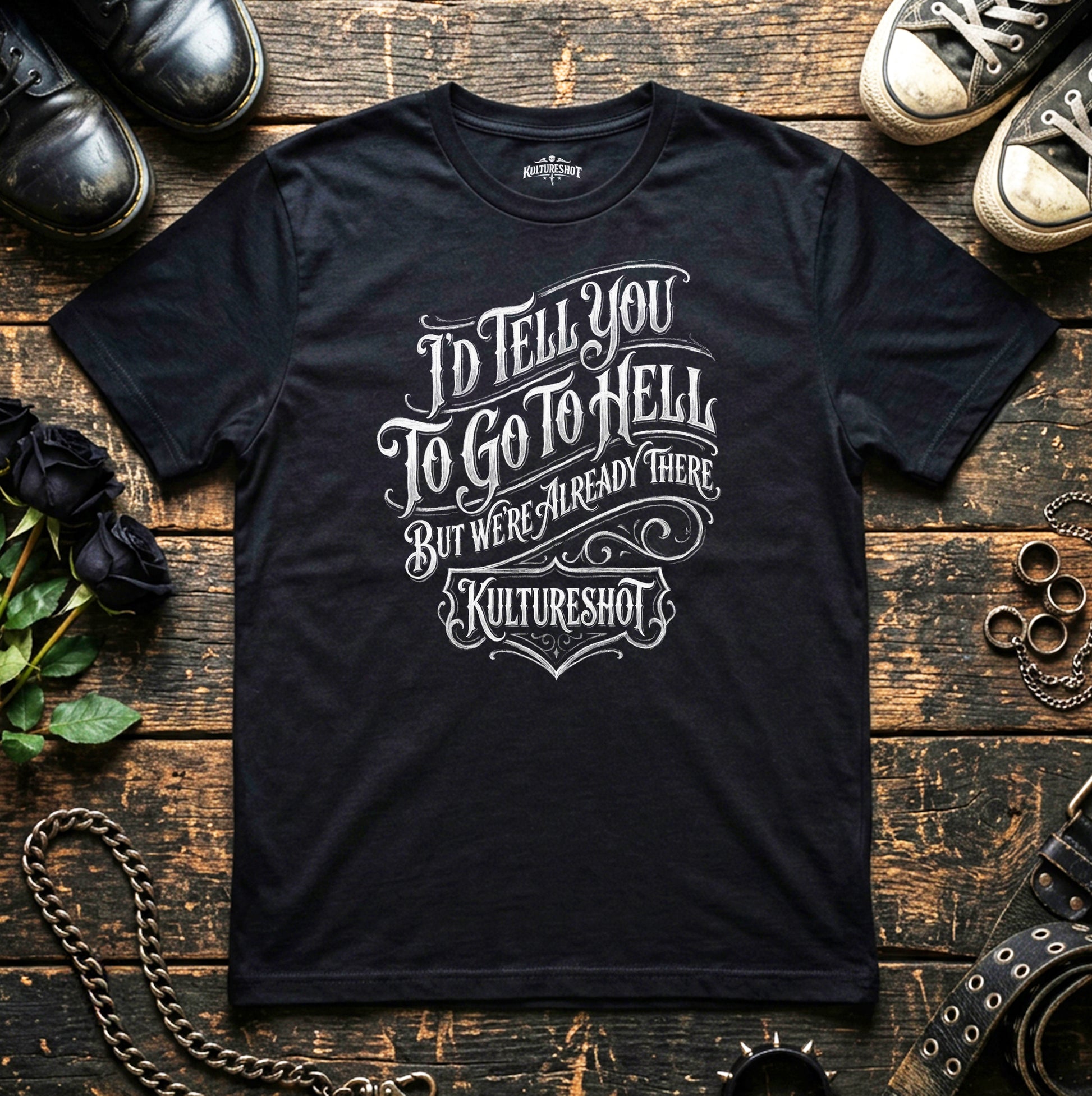 Black t-shirt with white text on a wooden surface with shoes and chains.