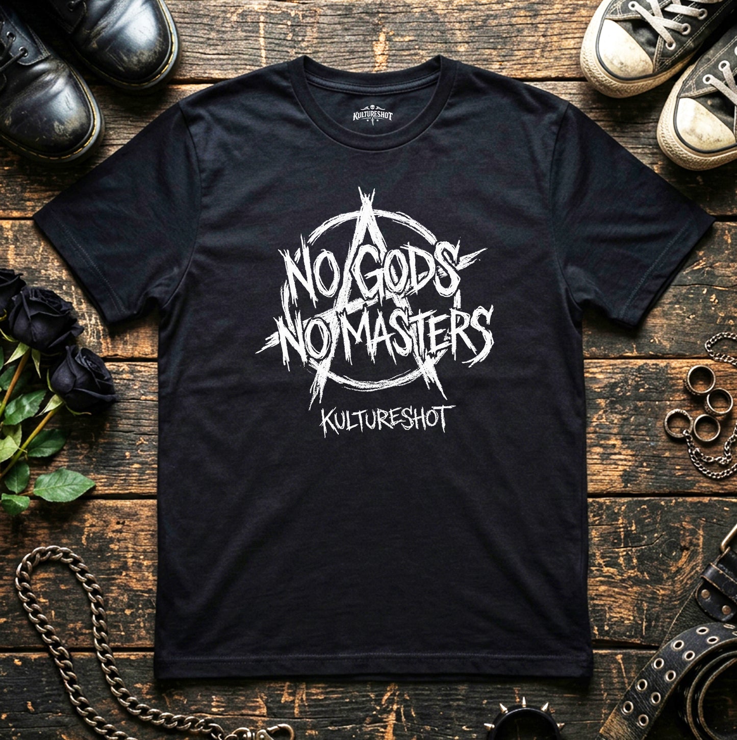 Black t-shirt with 'No Gods No Masters' design on a wooden surface with shoes and chains.