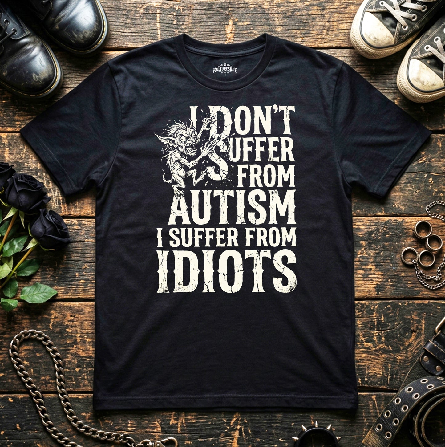 Black t-shirt with white text on a wooden surface with shoes and decorative items.