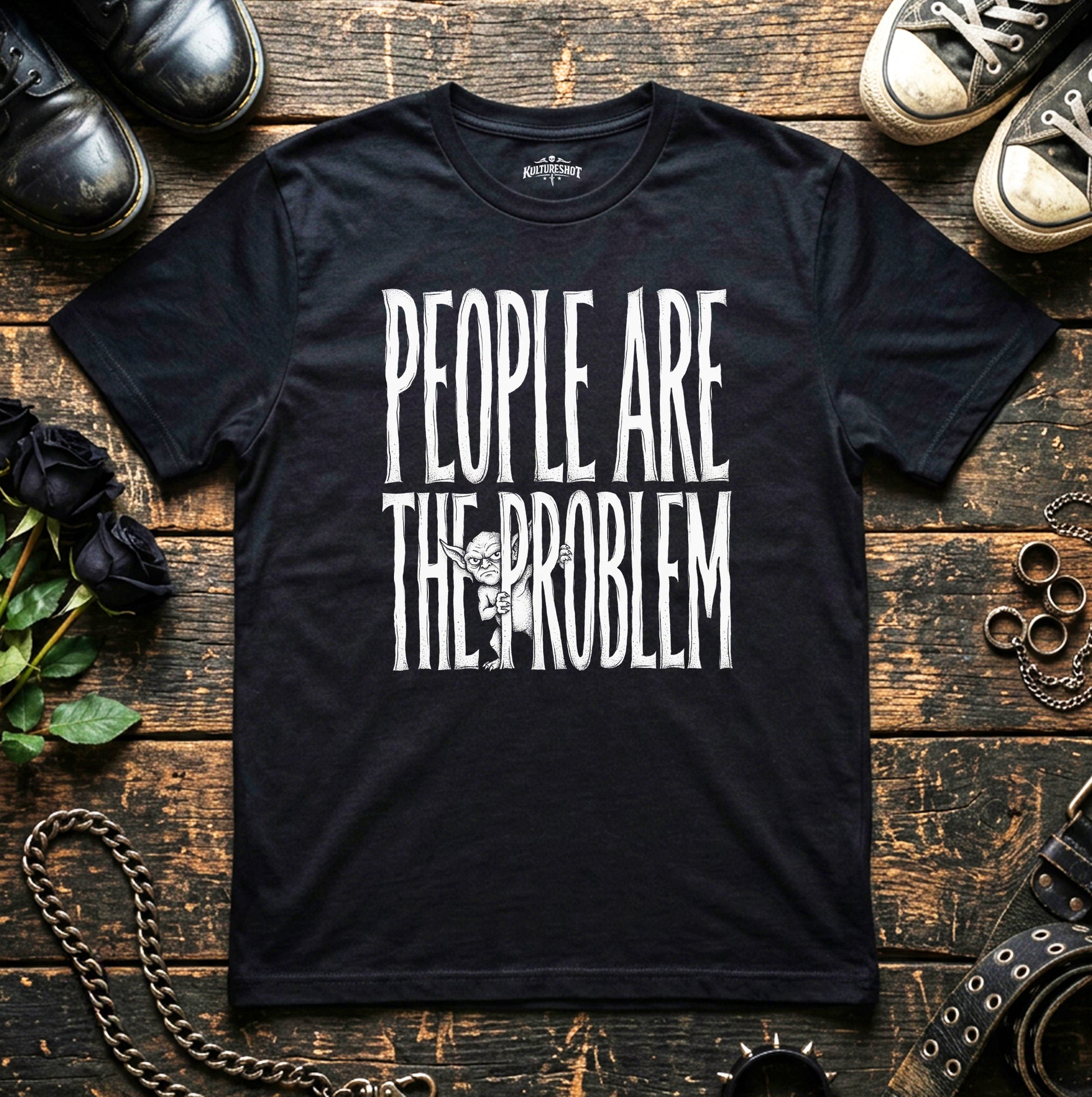Black t-shirt with 'People Are The Problem' text on a wooden surface with shoes and chains.