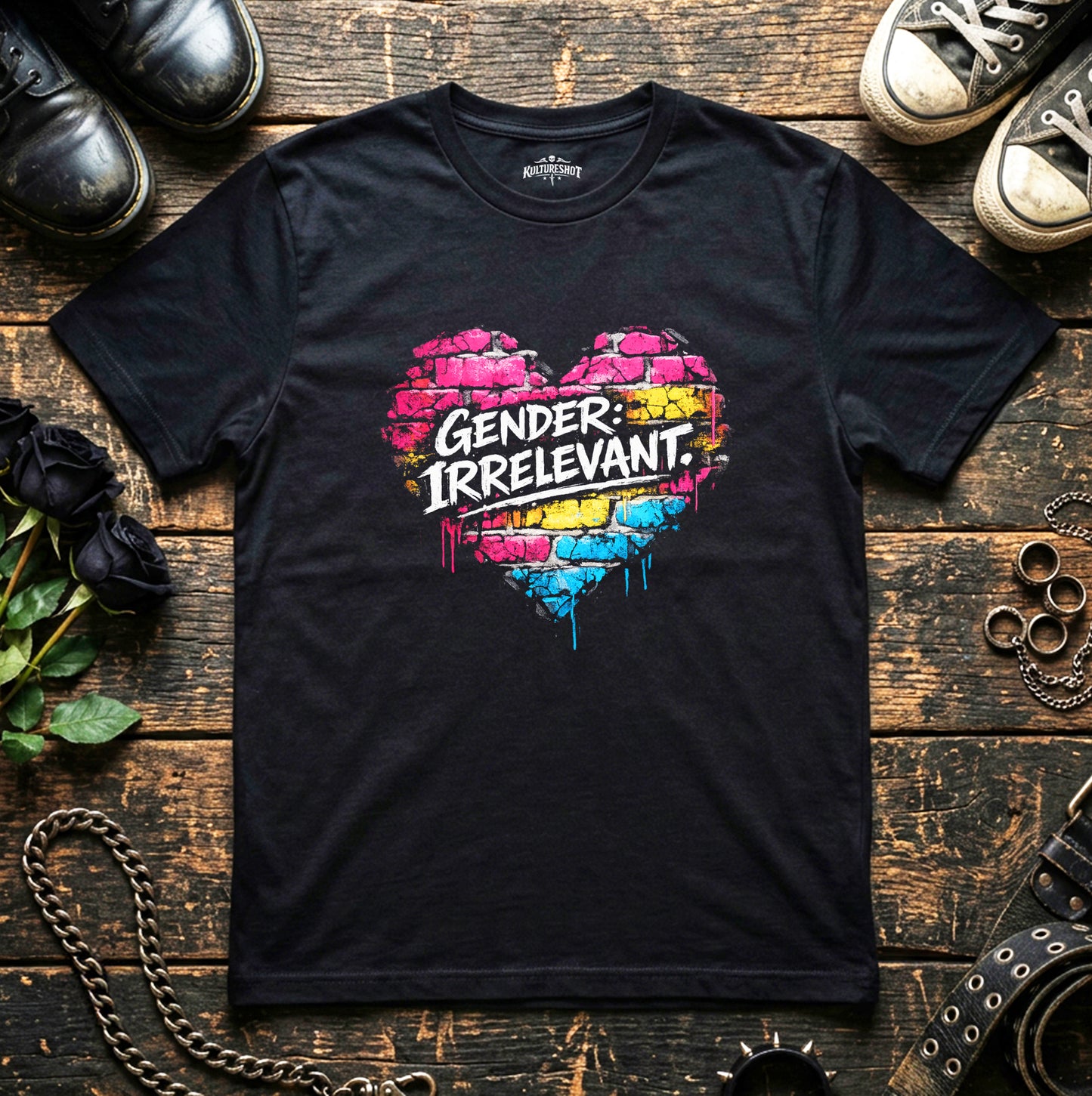 Black t-shirt with colorful heart design and 'Gender: Irrelevant' text on a wooden surface with shoes and flowers.