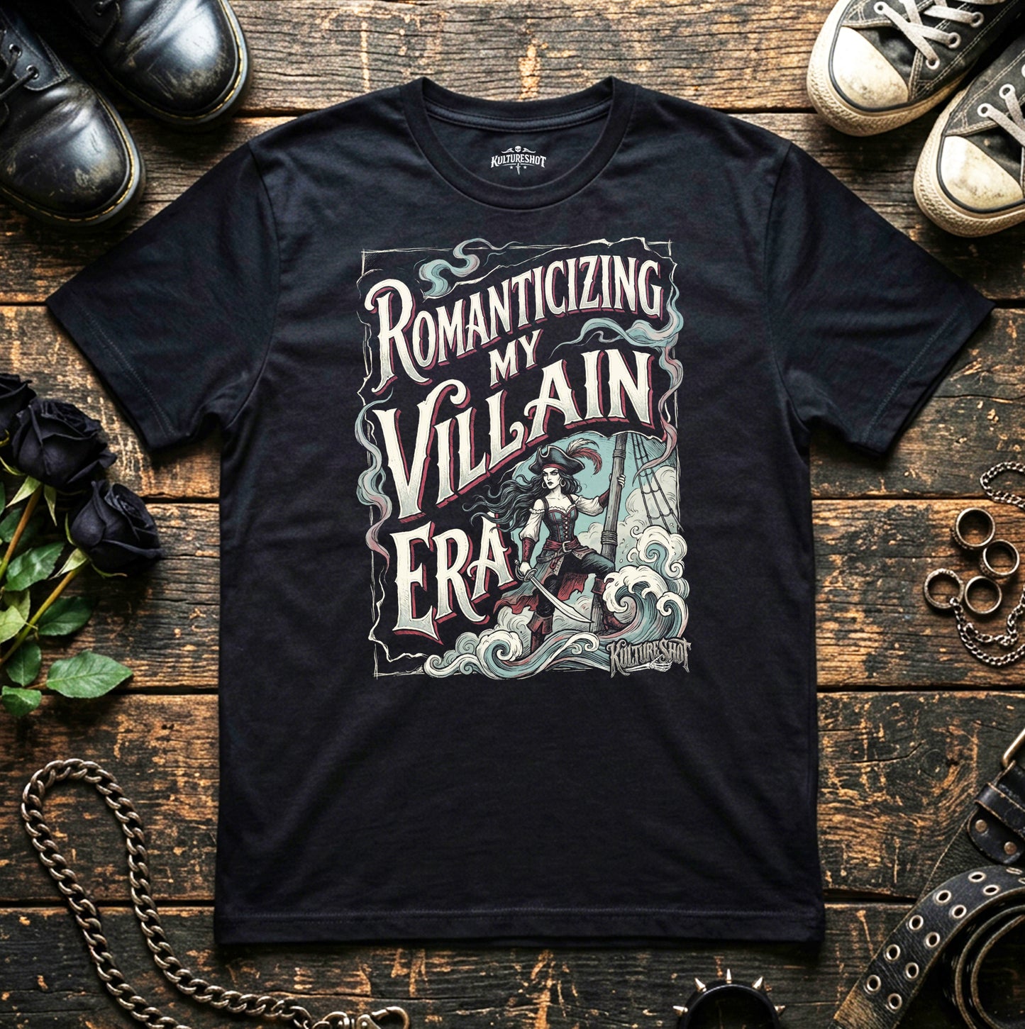 Black t-shirt with graphic design and text on a wooden surface with shoes and roses.