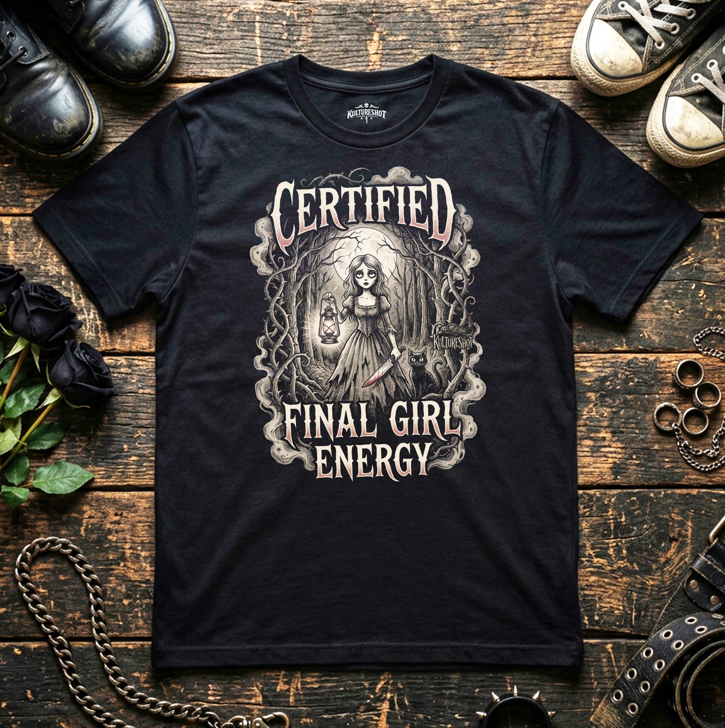 Black t-shirt with 'Certified Final Girl Energy' design on a wooden surface with shoes and roses.