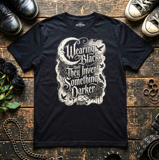 Black t-shirt with white graphic design on a wooden surface with shoes and roses.