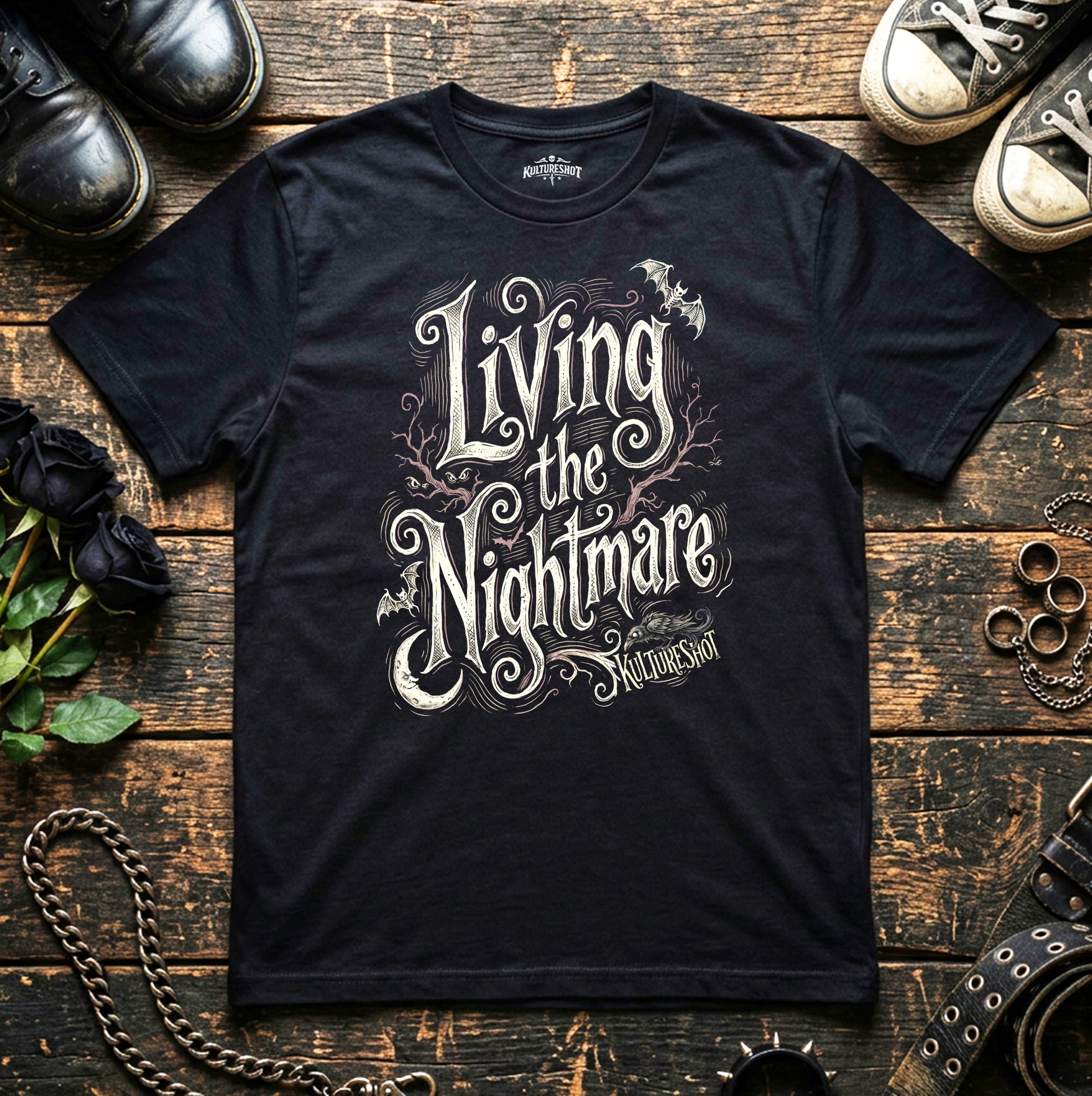Black t-shirt with 'Living the Nightmare' design on a wooden surface with shoes and roses.