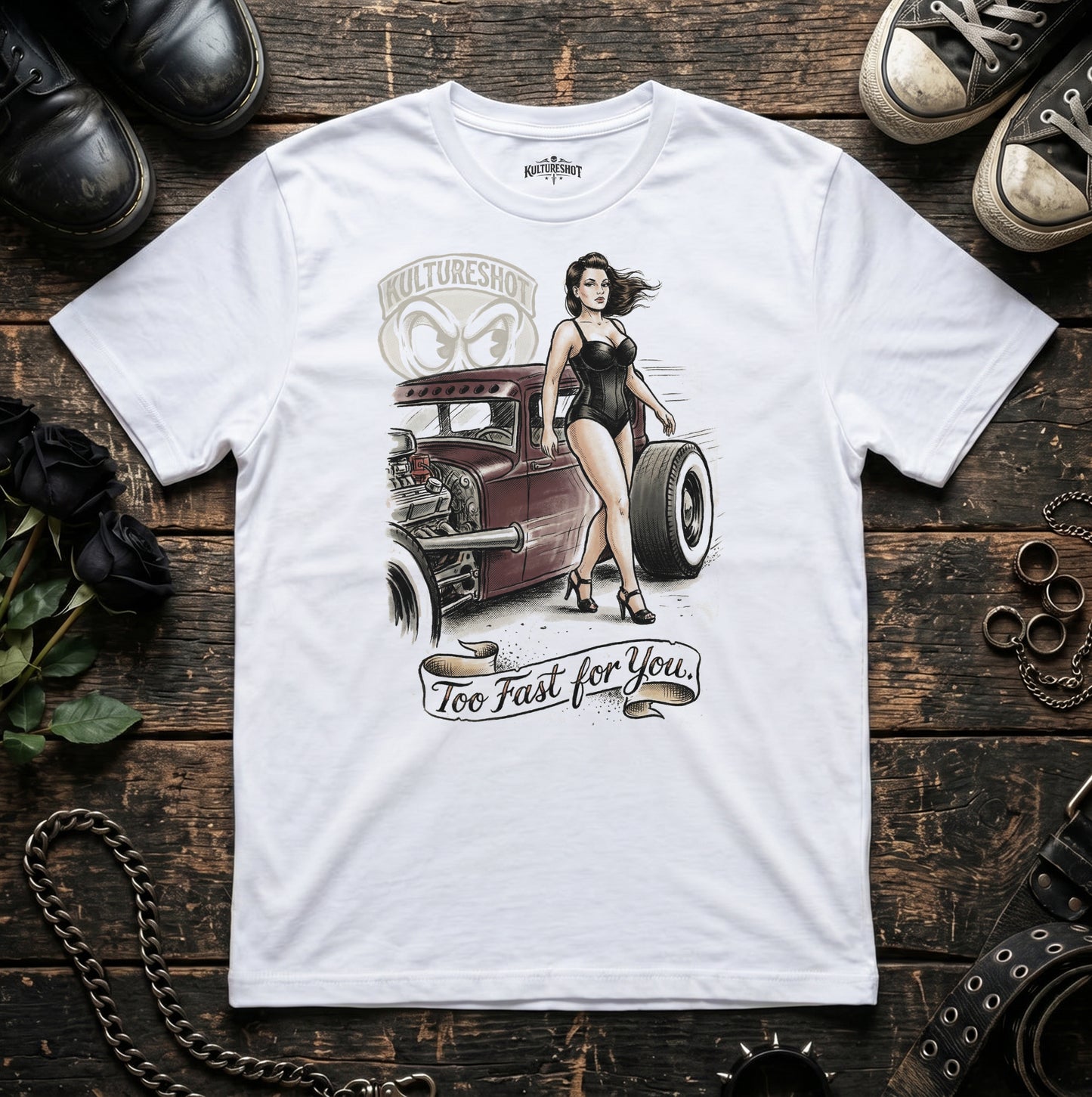White t-shirt with a graphic design of a woman next to a hot rod on a wooden surface.