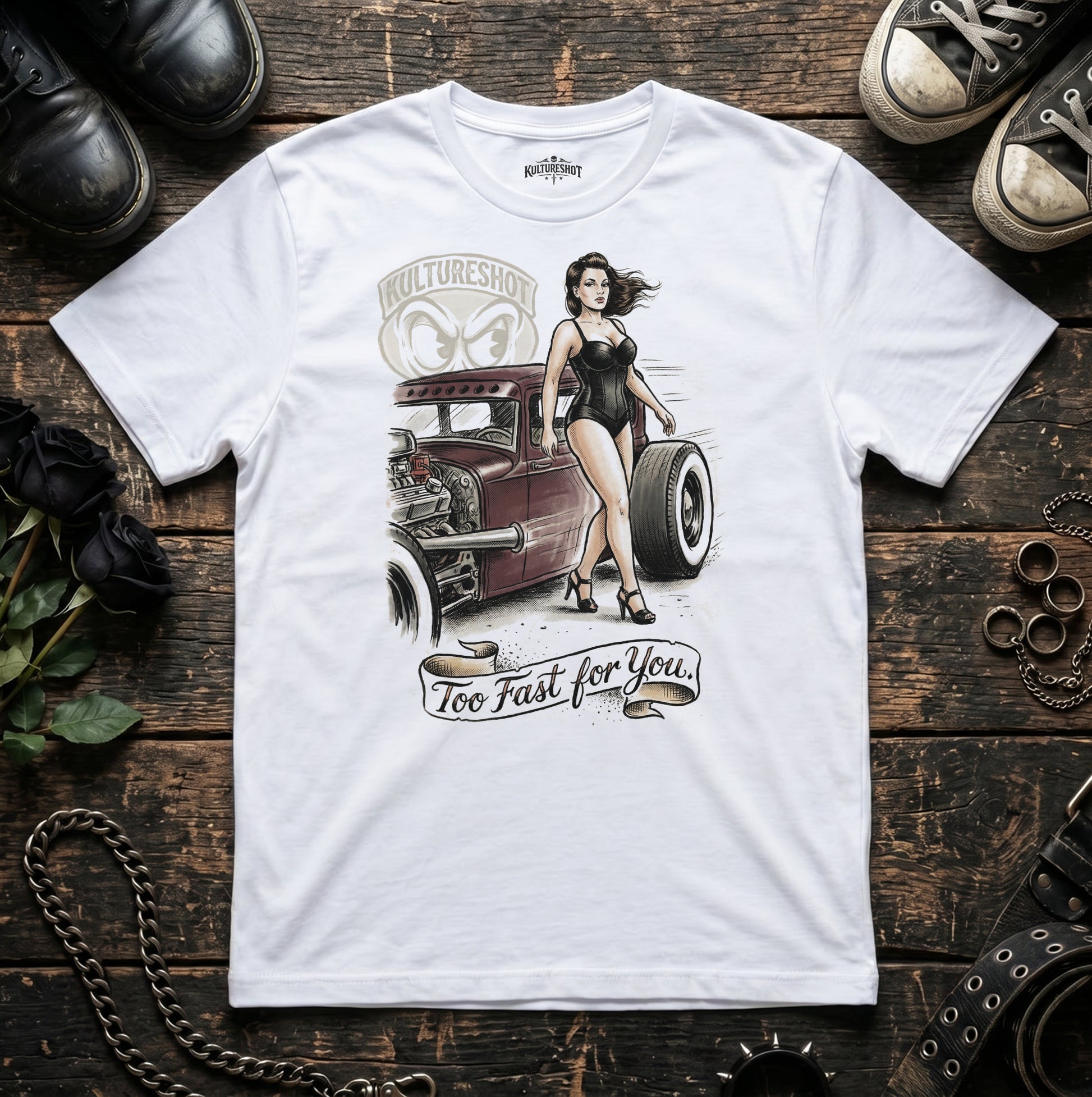 White t-shirt with a graphic design of a woman next to a hot rod on a wooden surface.