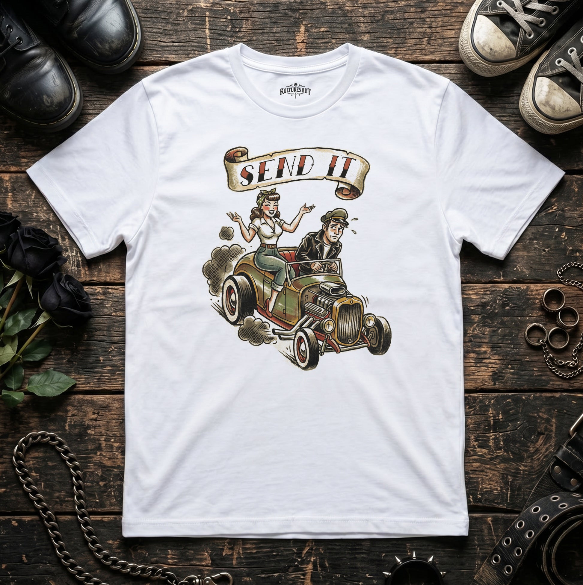 White t-shirt with a graphic of a couple in a vintage car and 'Send It' text, displayed on a wooden surface.