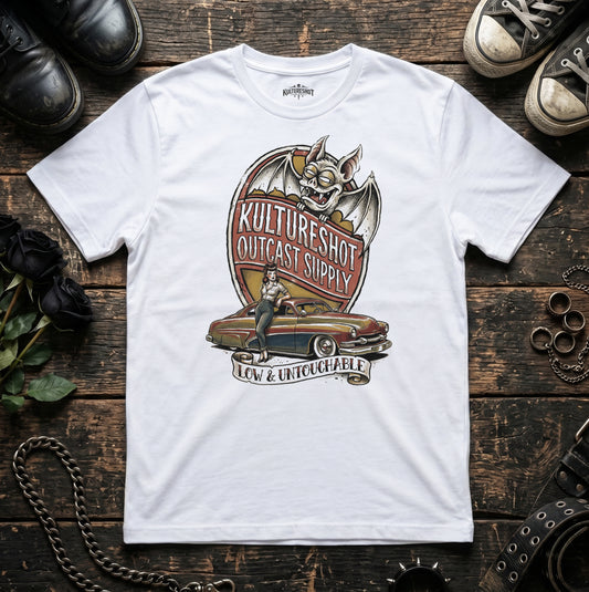 White t-shirt with a graphic design on a wooden surface with shoes and accessories.