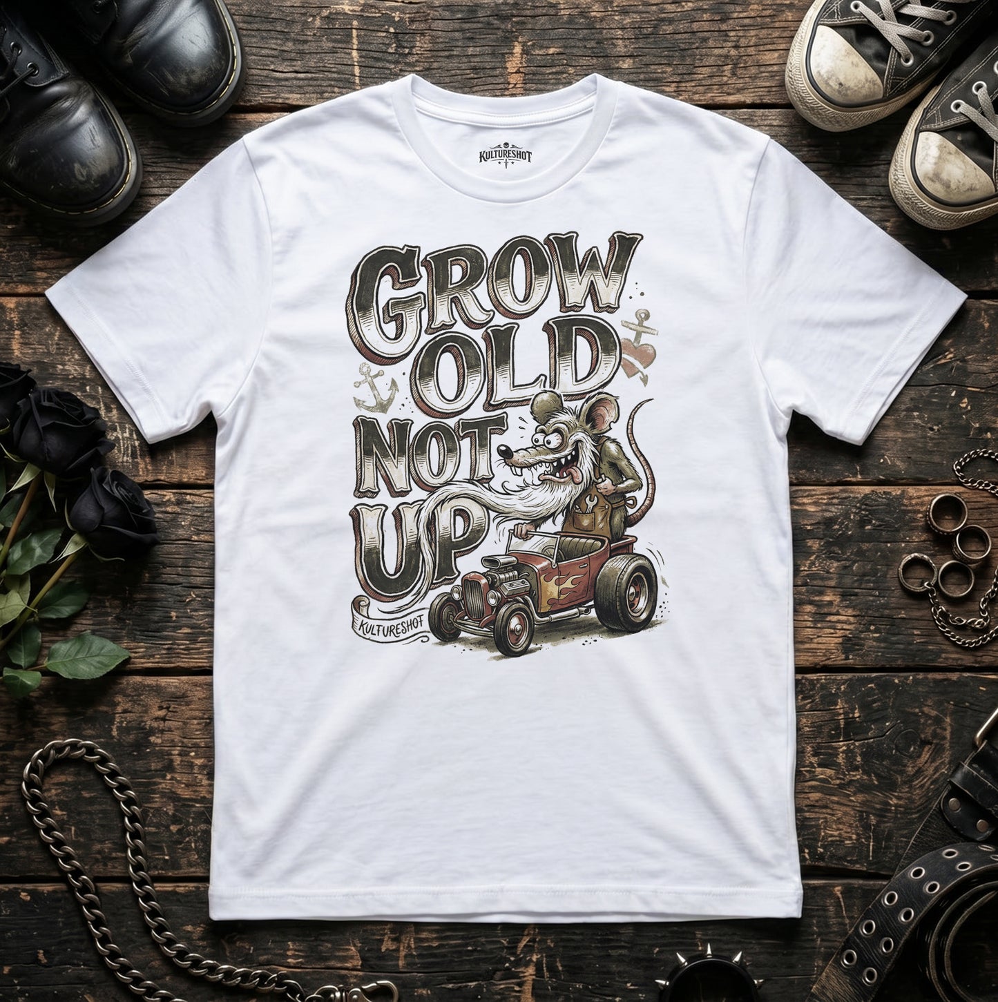 White t-shirt with graphic design and text on a wooden surface with shoes and accessories.