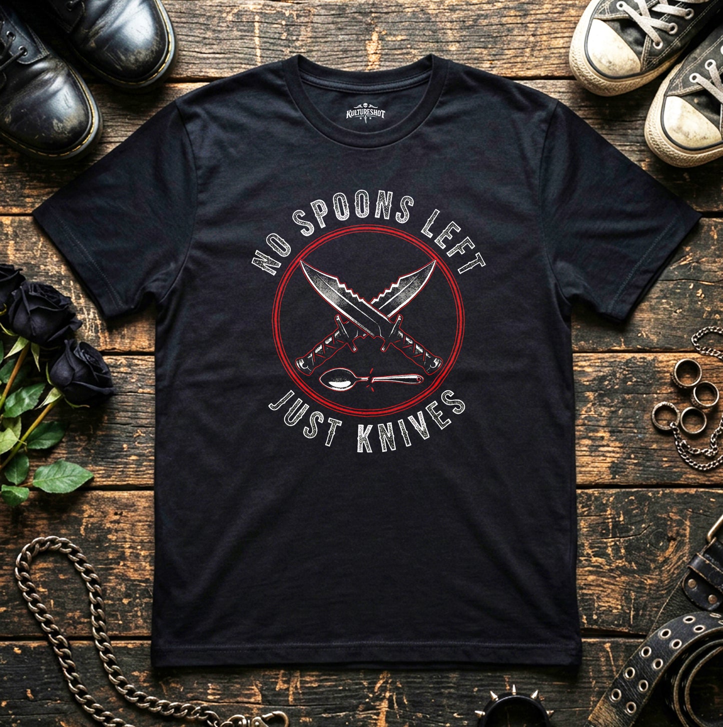 Black t-shirt with 'No Spoons Left Just Knives' graphic on a wooden surface with shoes and chains.