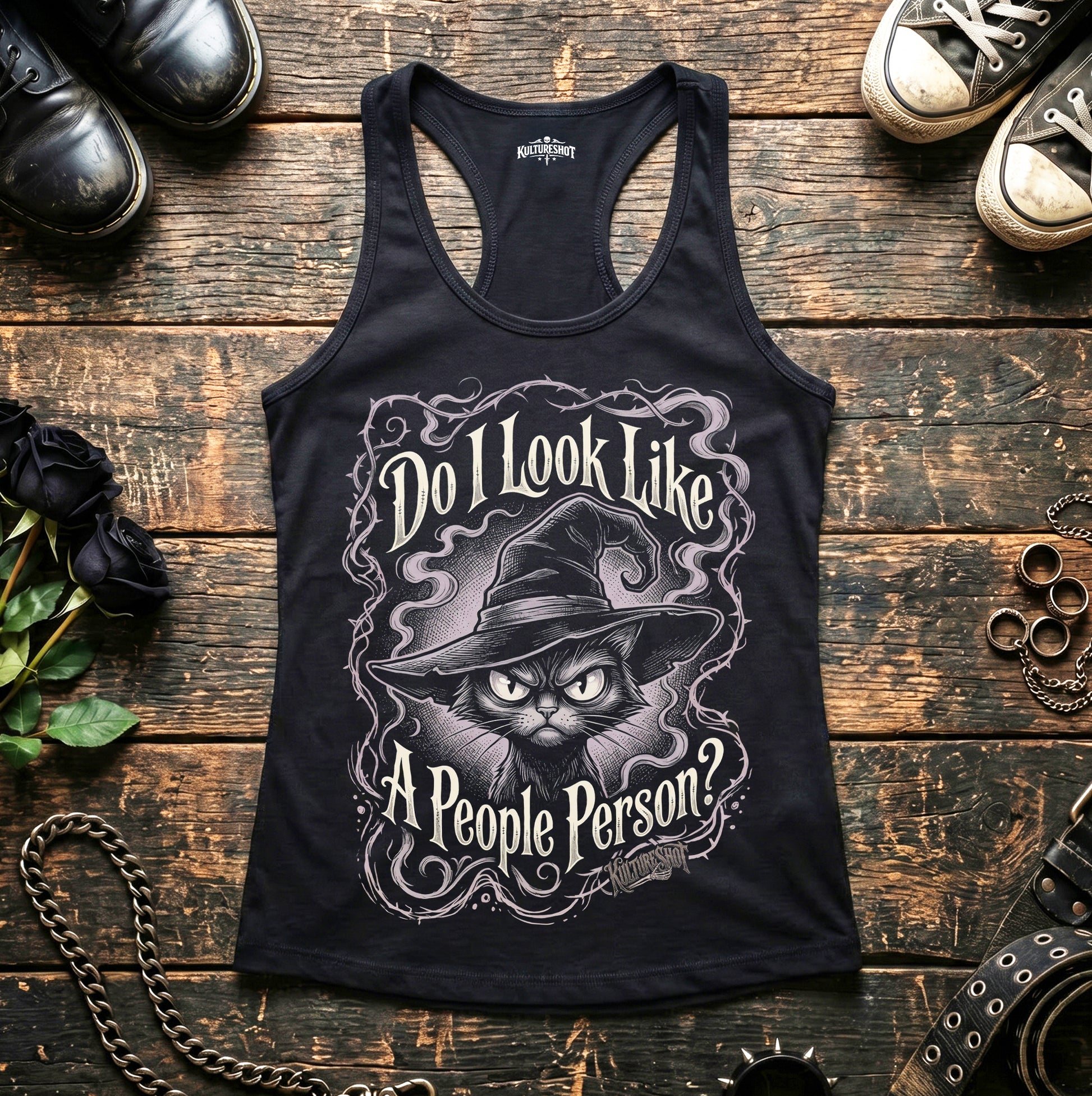 Black tank top with a cat graphic and text on a wooden surface with shoes and accessories.