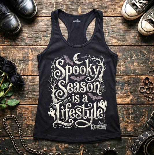 Black tank top with 'Spooky Season is a Lifestyle' text on a wooden surface with shoes and decorative items.
