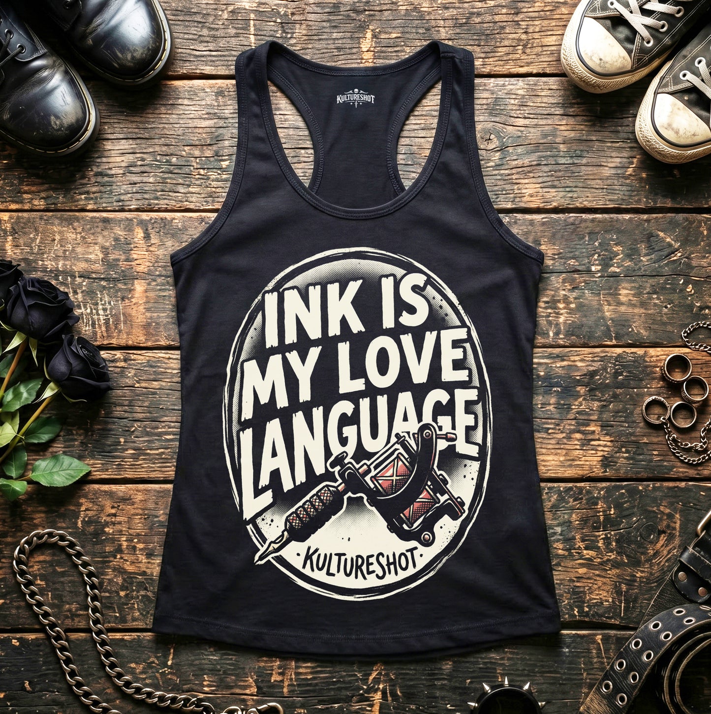 Black tank top with 'Ink is my Love Language' design on a wooden surface with shoes and jewelry.