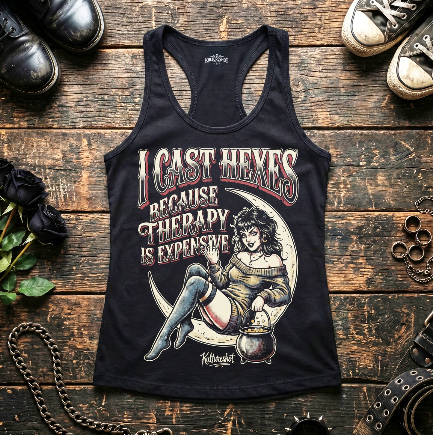 Black tank top with graphic design and text on a wooden surface with shoes and decorative items.