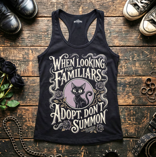 Black tank top with cat graphic and text on a wooden surface with shoes and decorative items.