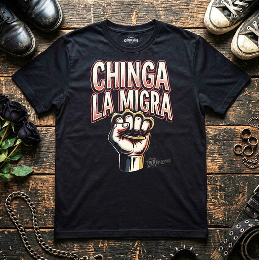 Black t-shirt with 'Chinga La Migra' graphic on a wooden surface with shoes and plants.