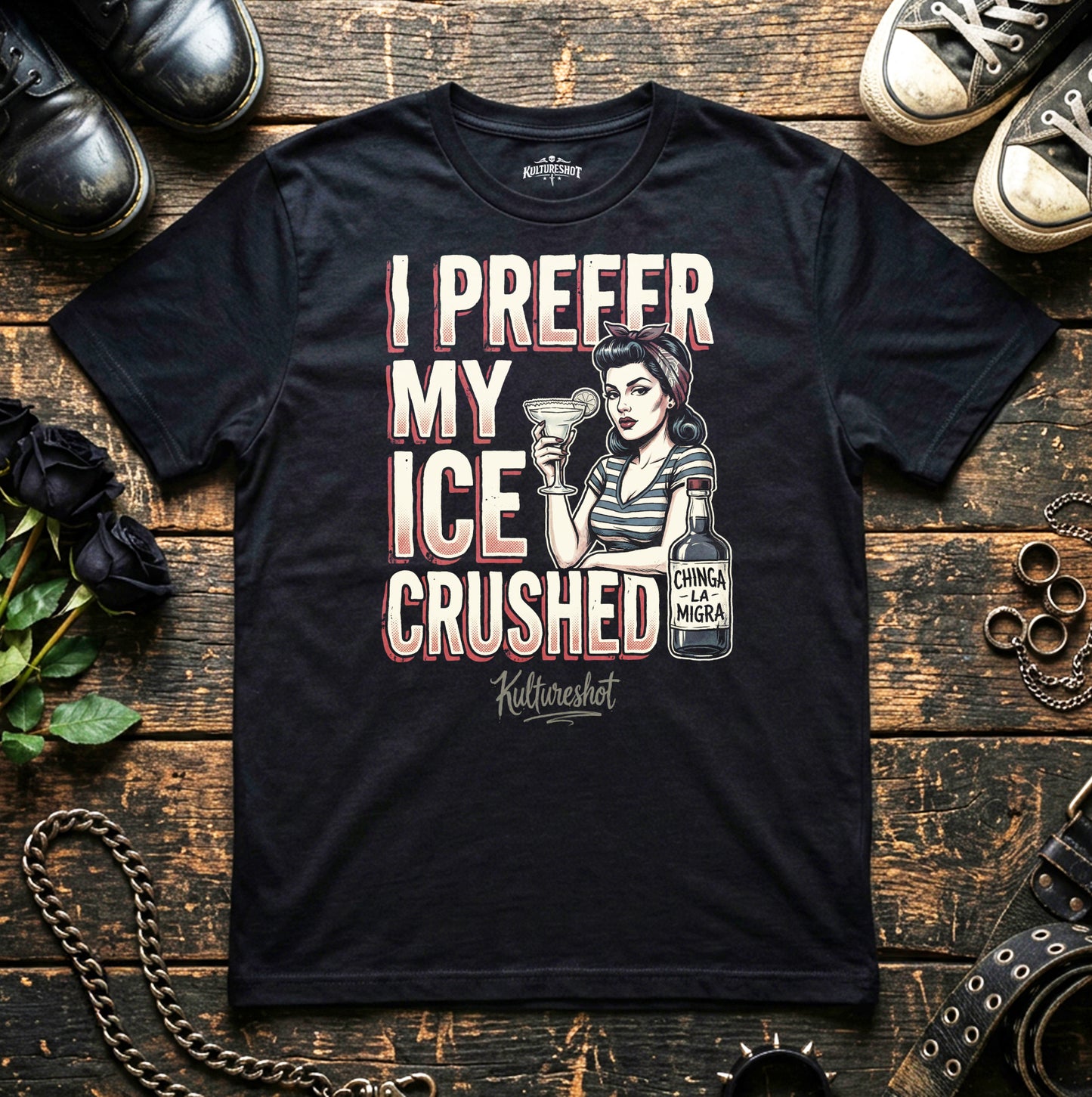 Black t-shirt with graphic design and text on a wooden surface with shoes and flowers.
