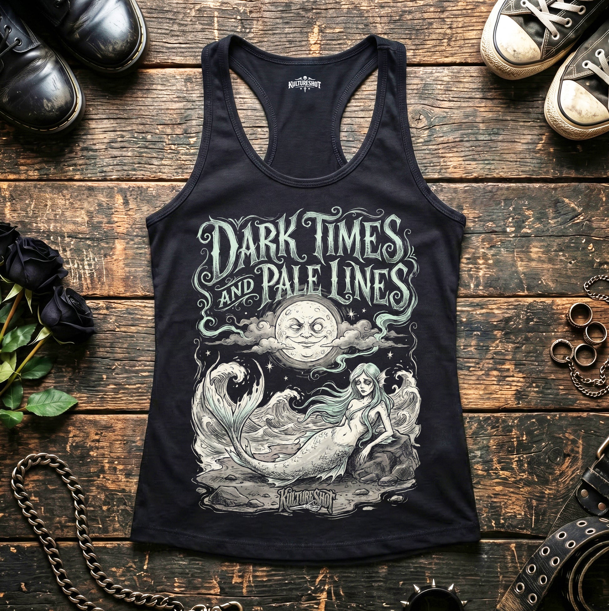 Black tank top with 'Dark Times and Pale Lines' design on a wooden surface with shoes and decorative items.